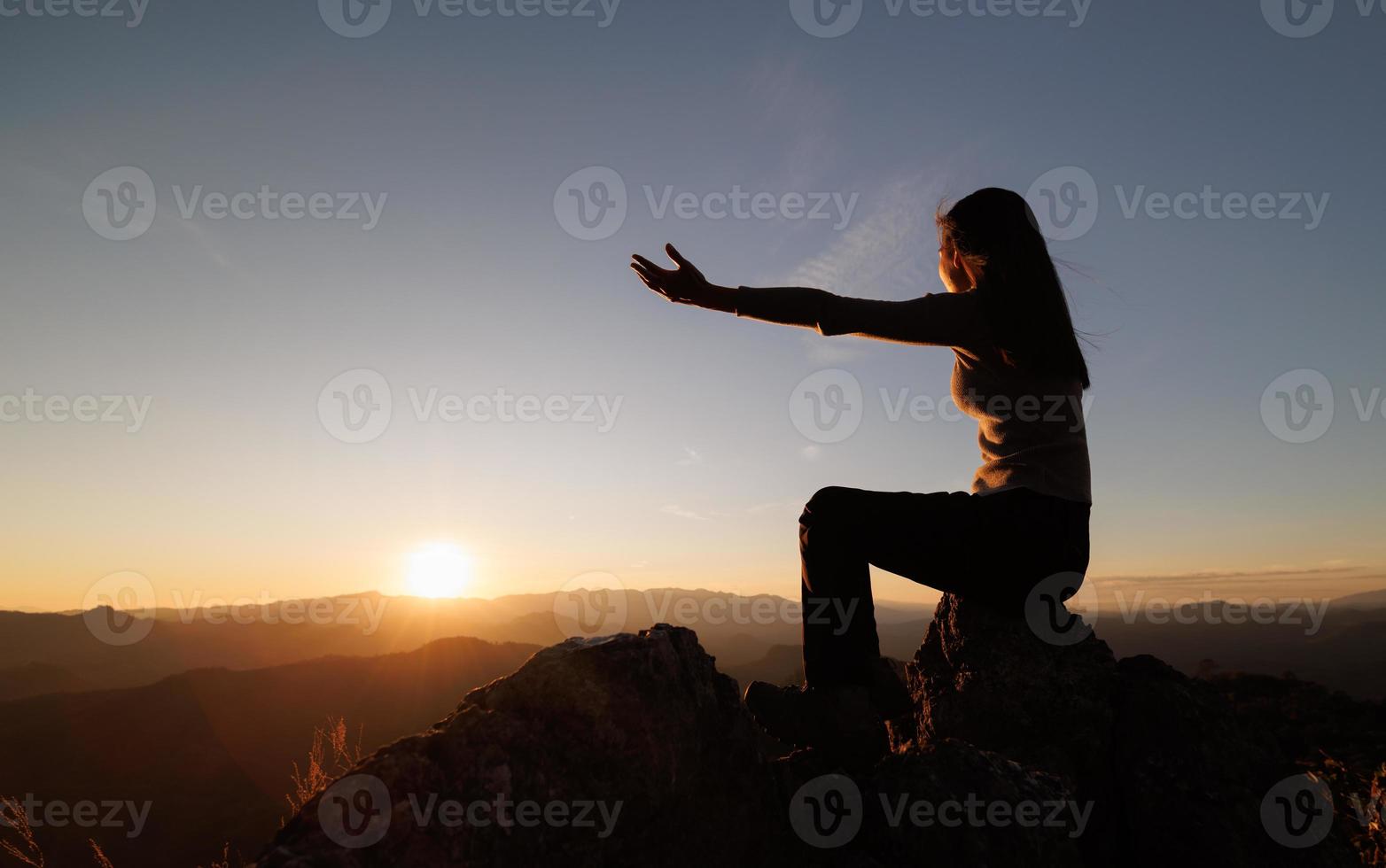 Silhouette of  man rise hand up on top of mountain and sunset sky abstract background. Freedom and travel adventure concept. pray or Praying, remembering God, Copy space . photo