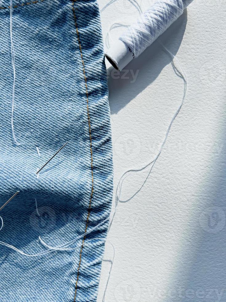 needle and thread. mending jeans photo