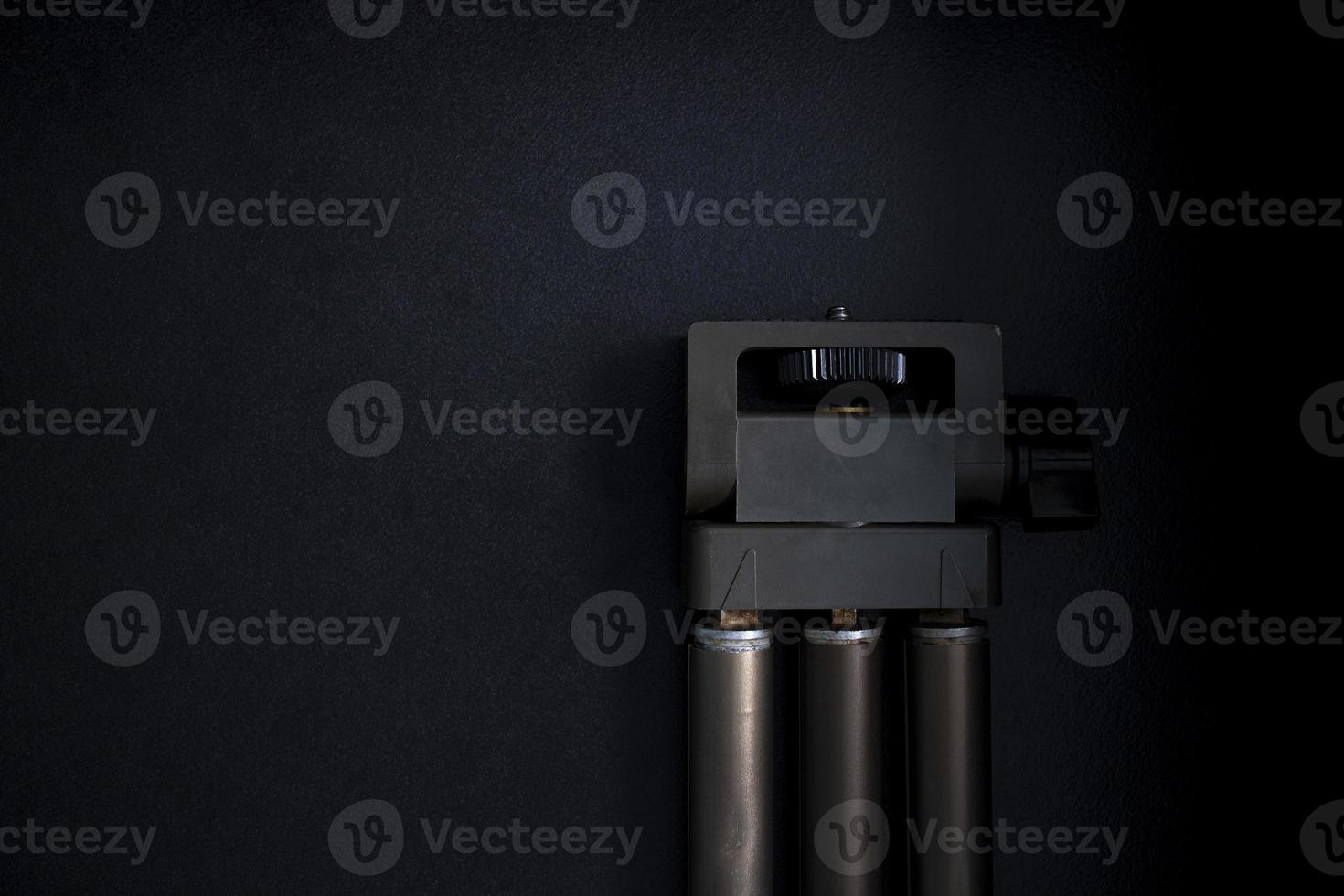 Beautiful old camera tripod on black background in dark room with studio lights photo