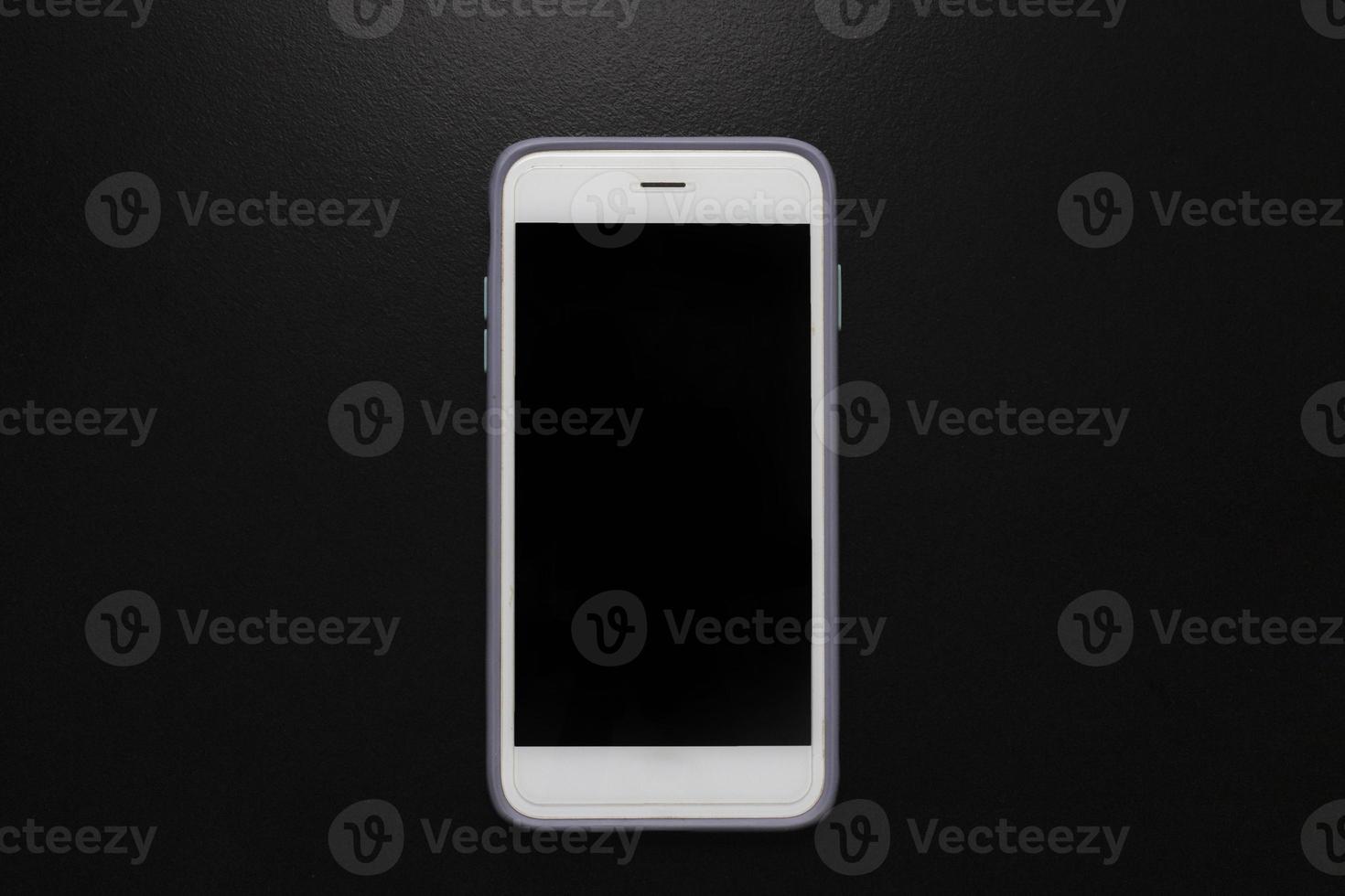 Mobile phone with black blank screen on black background with light from above. photo