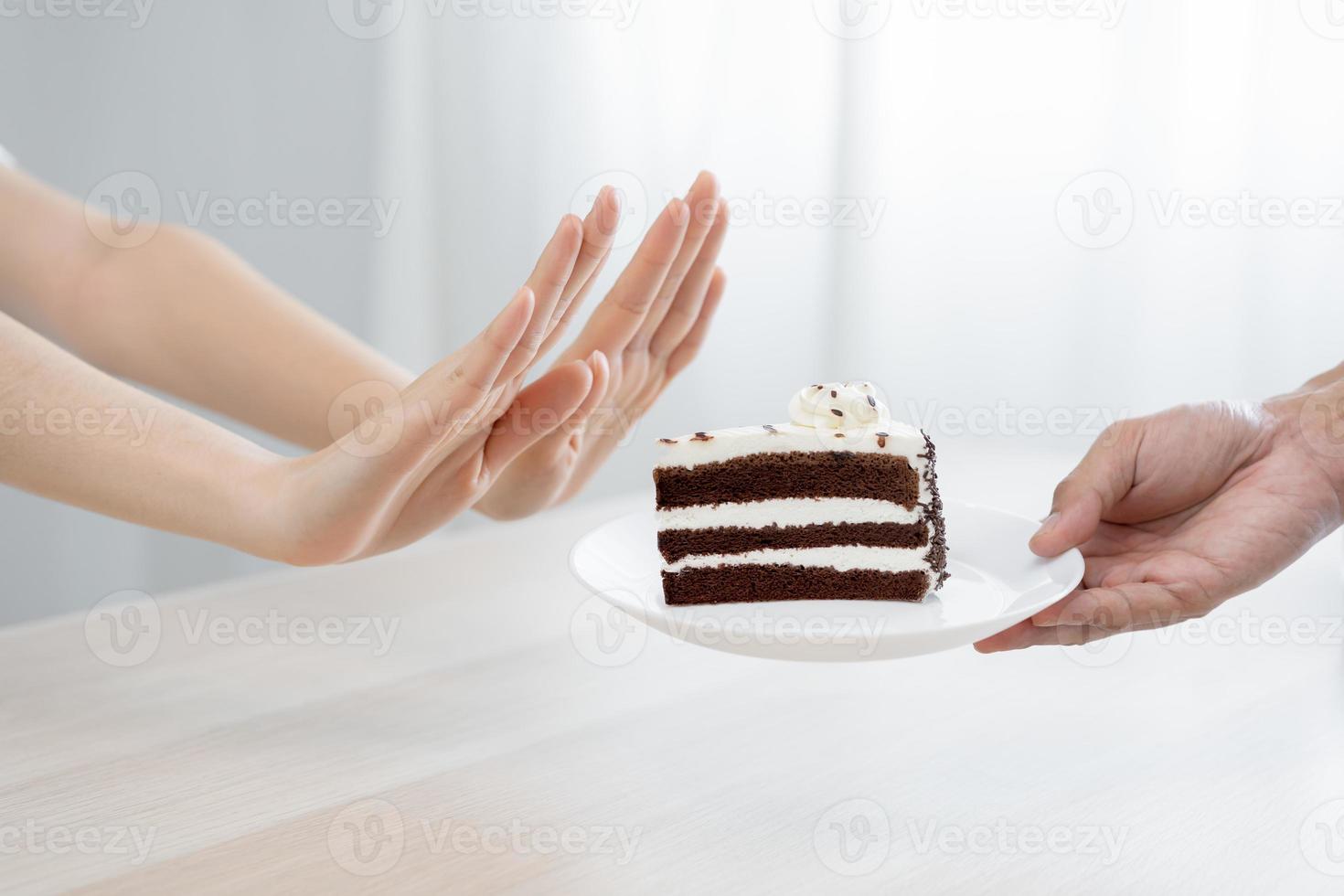 Diet, Dieting unhealthy asian young woman hand in push out, rejecting eat chocolate cake or sweet taste, fighting to keep it from getting fat when person bring to me. Healthy, nutrition of weight loss photo