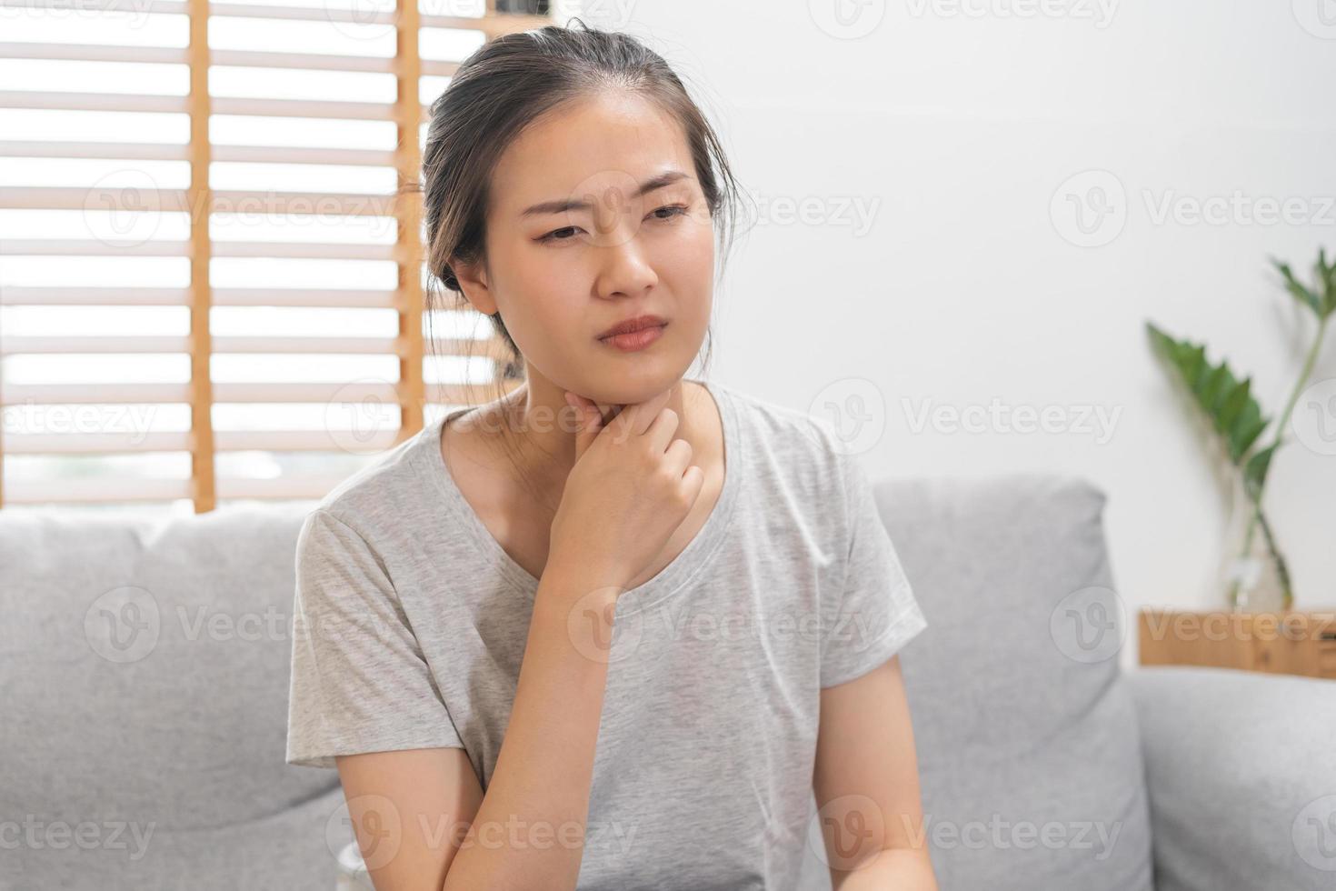 Sick, hurt or pain asian young woman, girl with sore throat, cough have a fever, flu and sneezing nose, runny sitting on sofa bed at home. Health care person on virus seasonal. photo