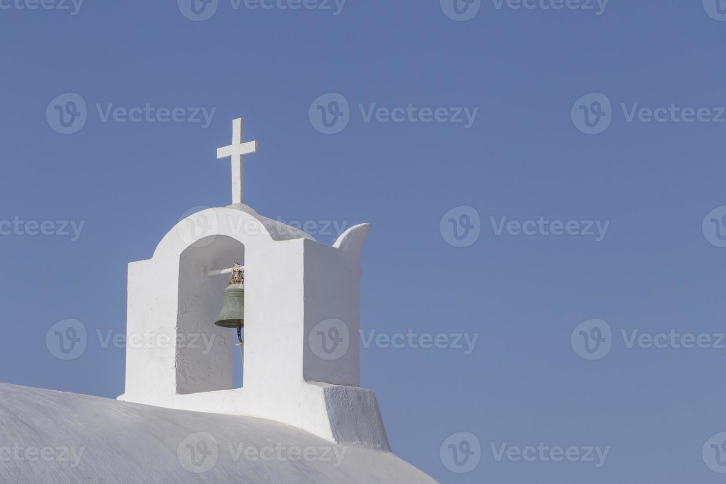 bell tower on chapel on Santorini against clear blue sky photo