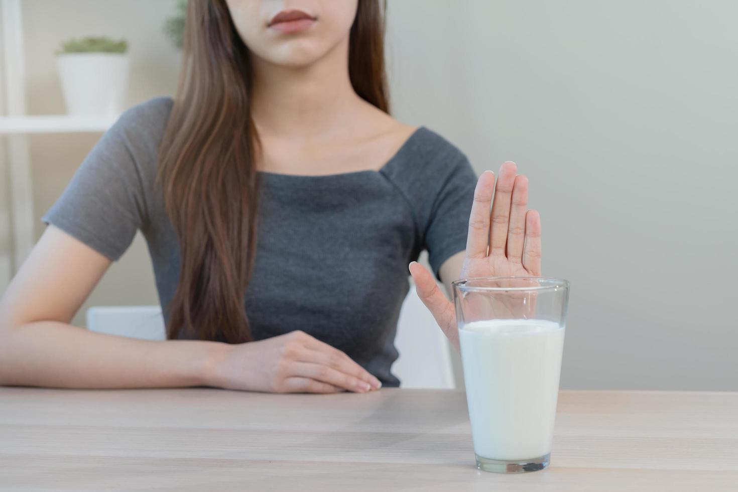 alergia asiático joven mujer, niña mano en denegar, No o empujar fuera a evitar para bebida Leche a hogar, infeliz y malo estómago dolor. lactosa intolerancia y lechería alimento, salud problema, barriga sufrir concepto. foto