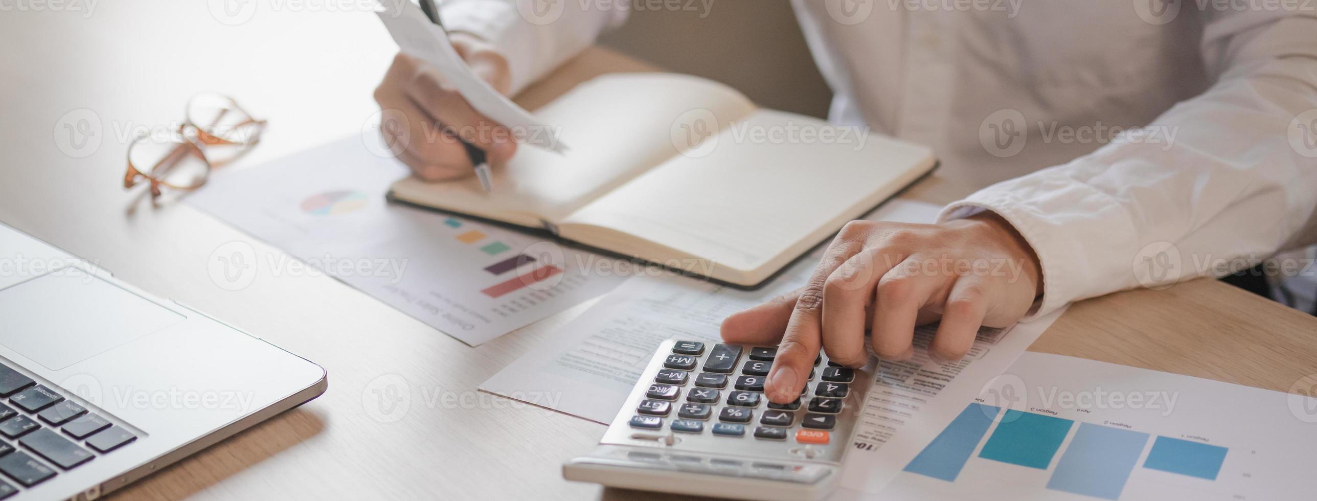 Close up hand of stress young asian businessman,male is pressing a calculator to calculate tax income and expenses, bills, credit card for payment or payday at home, office.Financial, finance concept. photo
