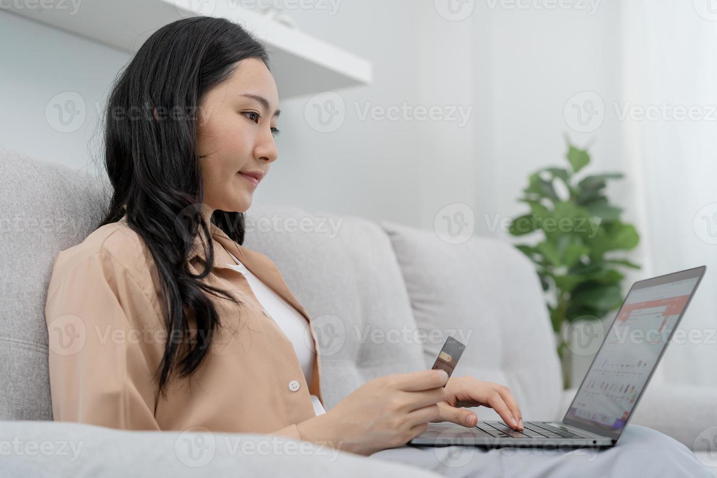 Internet banking, Online shopping at home, happy asian young woman, girl hand in holding credit card, using laptop computer, spending money with purchase, pay on store at home. Shopaholic e-commerce. photo