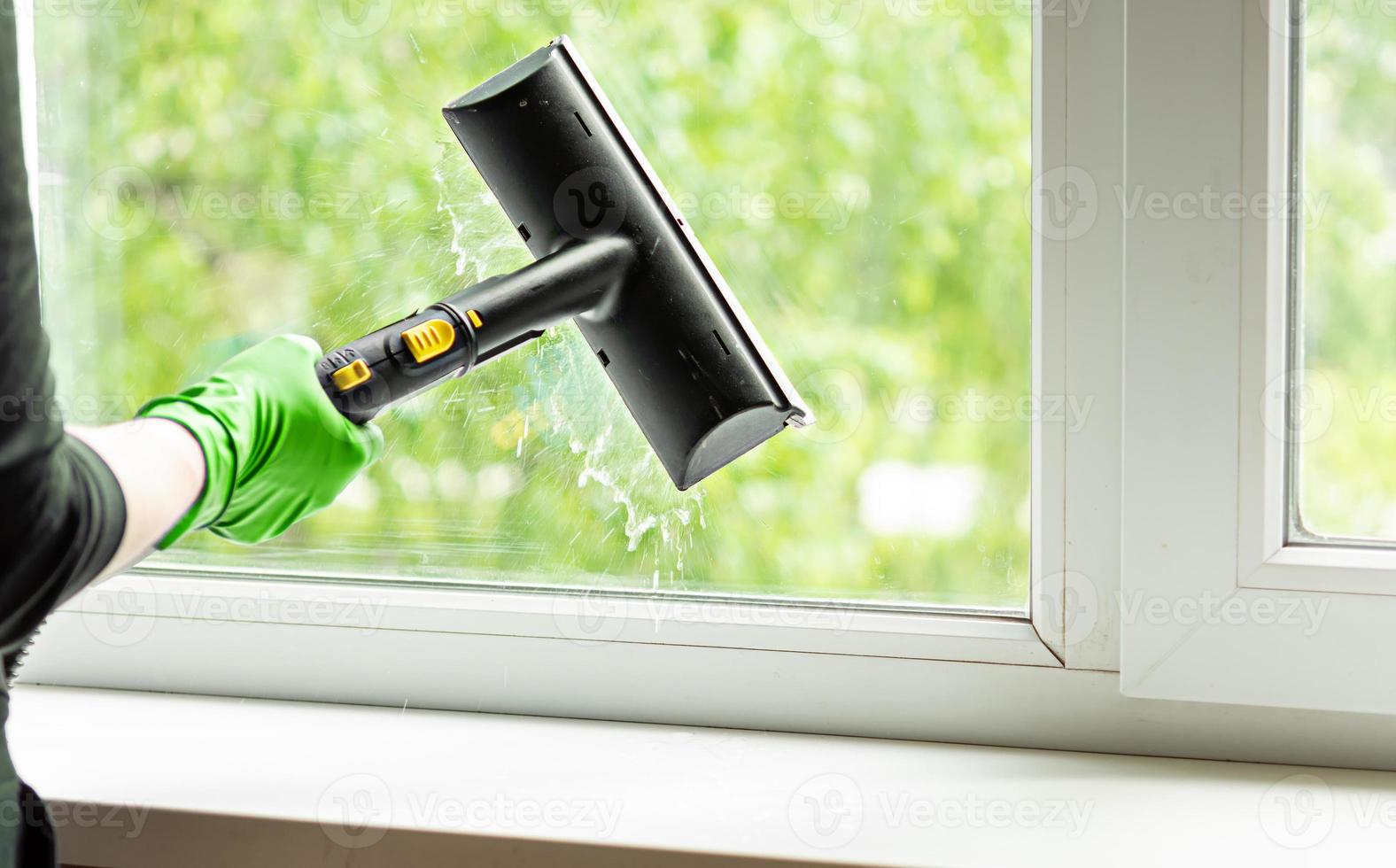 woman washes the windows of a house with a steam generator. To clean up the house in the spring. House cleaning. photo