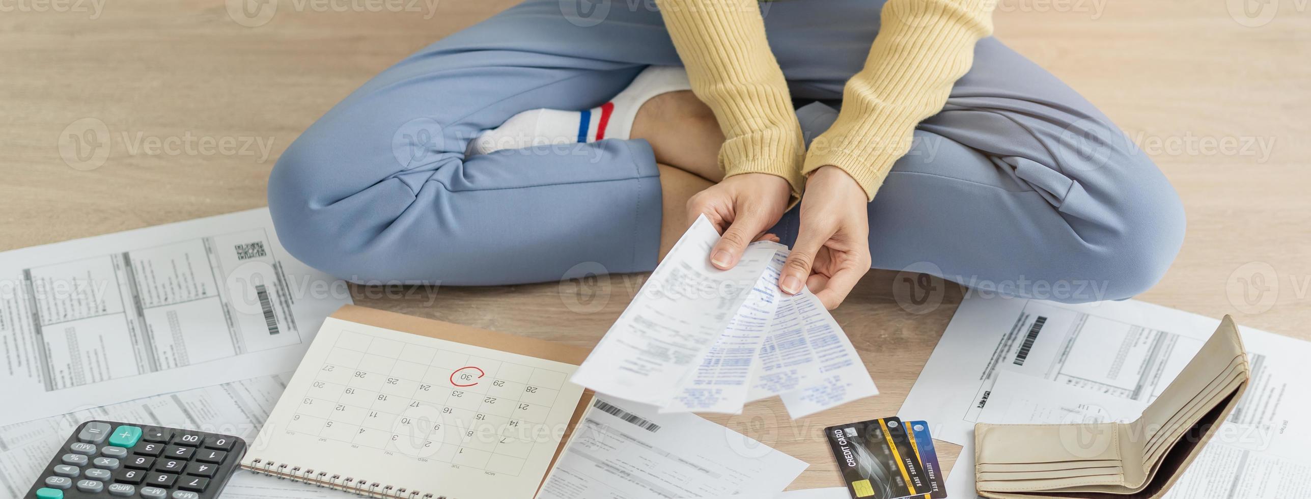 financiero deber asiático mujer, hembra sentado en piso hogar, estresado y confuso por calcular gastos desde factura o factura, tener No dinero a pagar, hipoteca o préstamo. deuda, bancarrota o arruinado concepto. foto