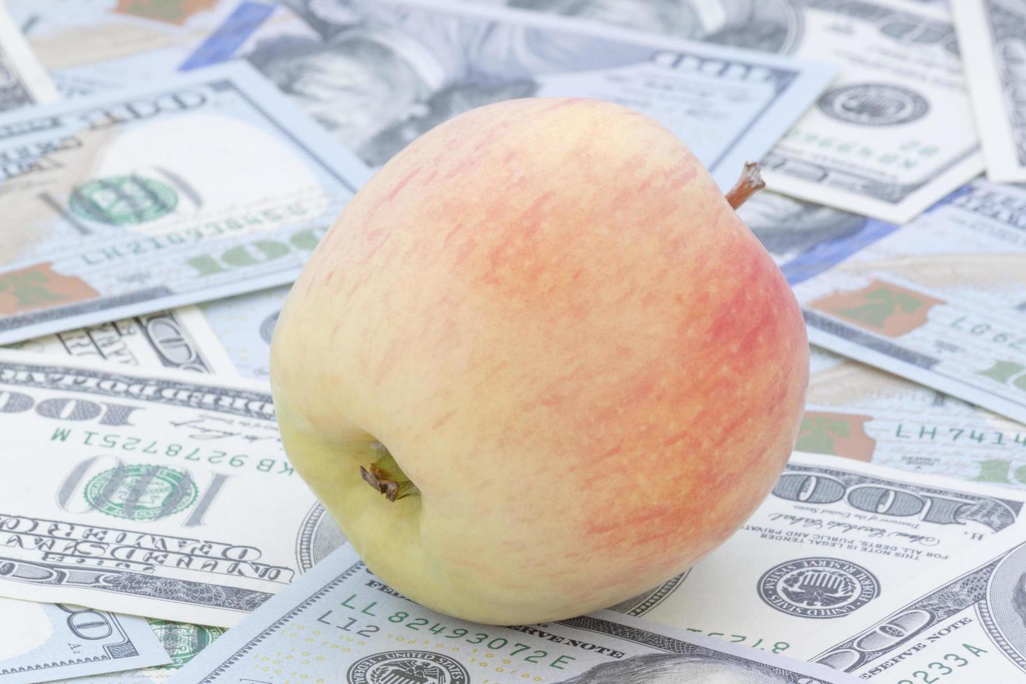 apple lying on heap of one hundred dollars banknotes photo