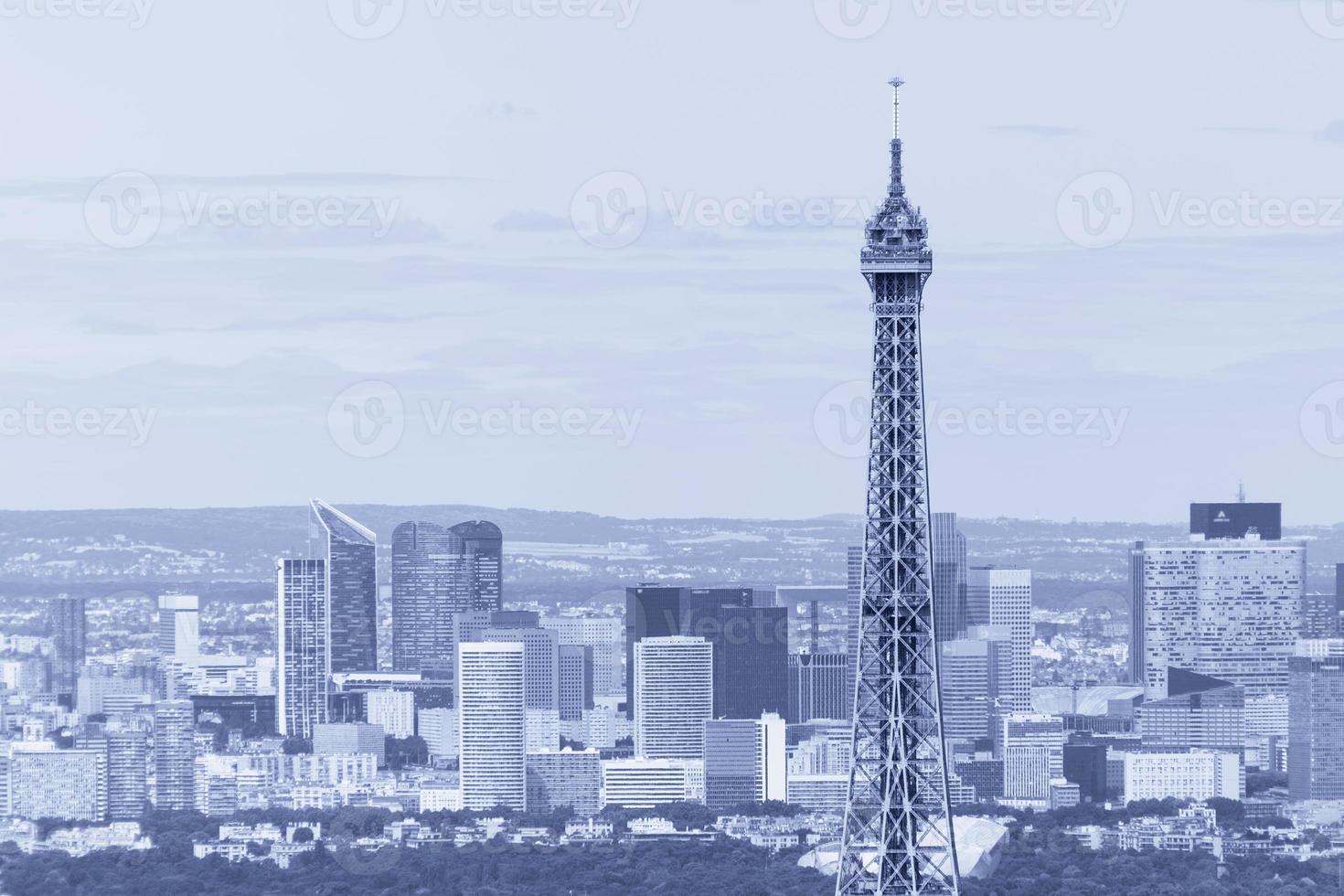 close up of top part of Eiffel tower against La Defense district photo