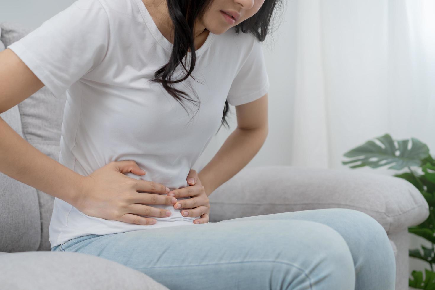 Flatulence asian young woman, girl hand in stomach ache, suffer from food poisoning, abdominal pain and colon problem, gastritis or diarrhoea. Patient belly, abdomen or inflammation, concept. photo