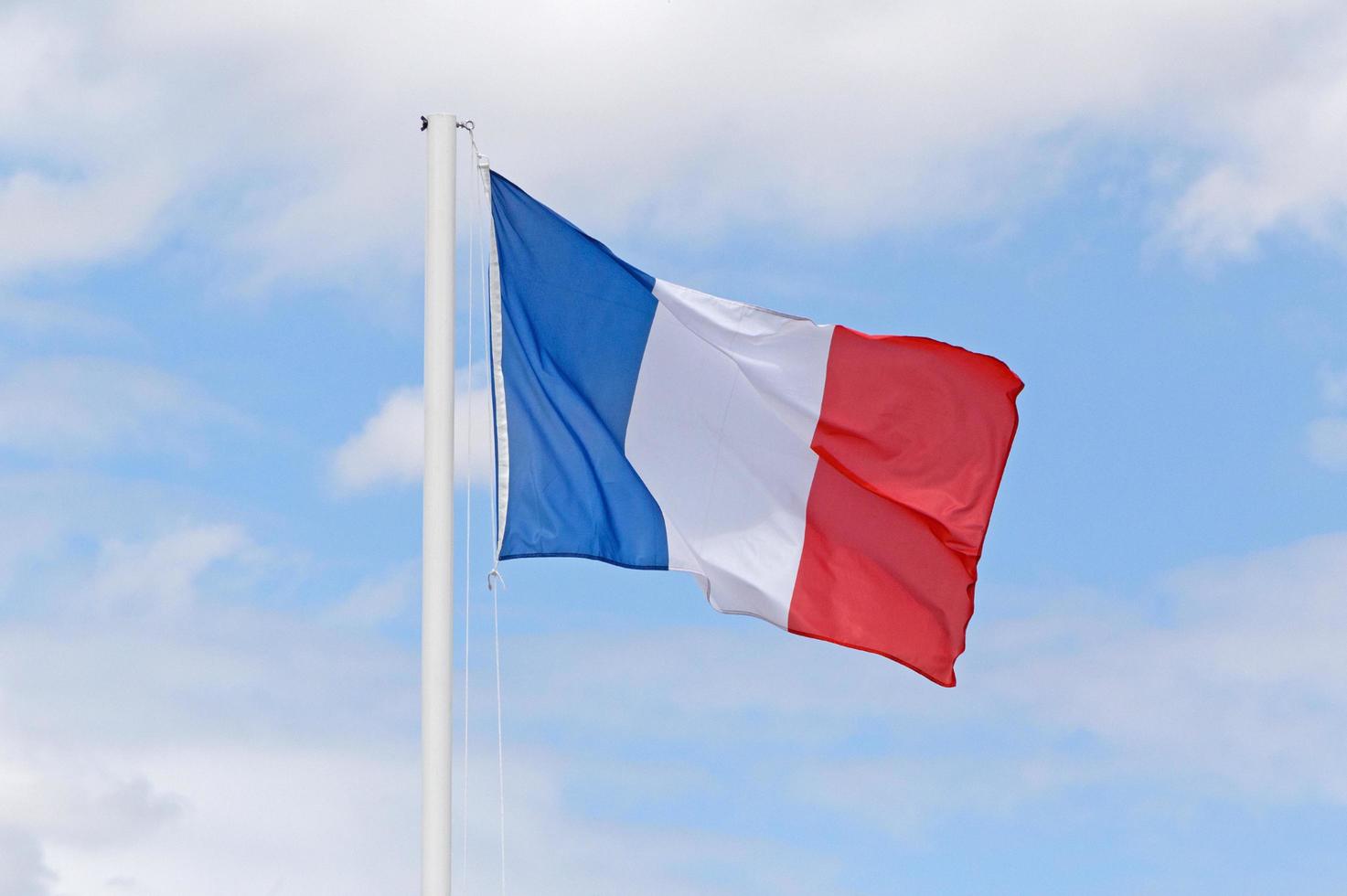 francés bandera en asta de bandera en contra azul cielo con blanco nubes foto