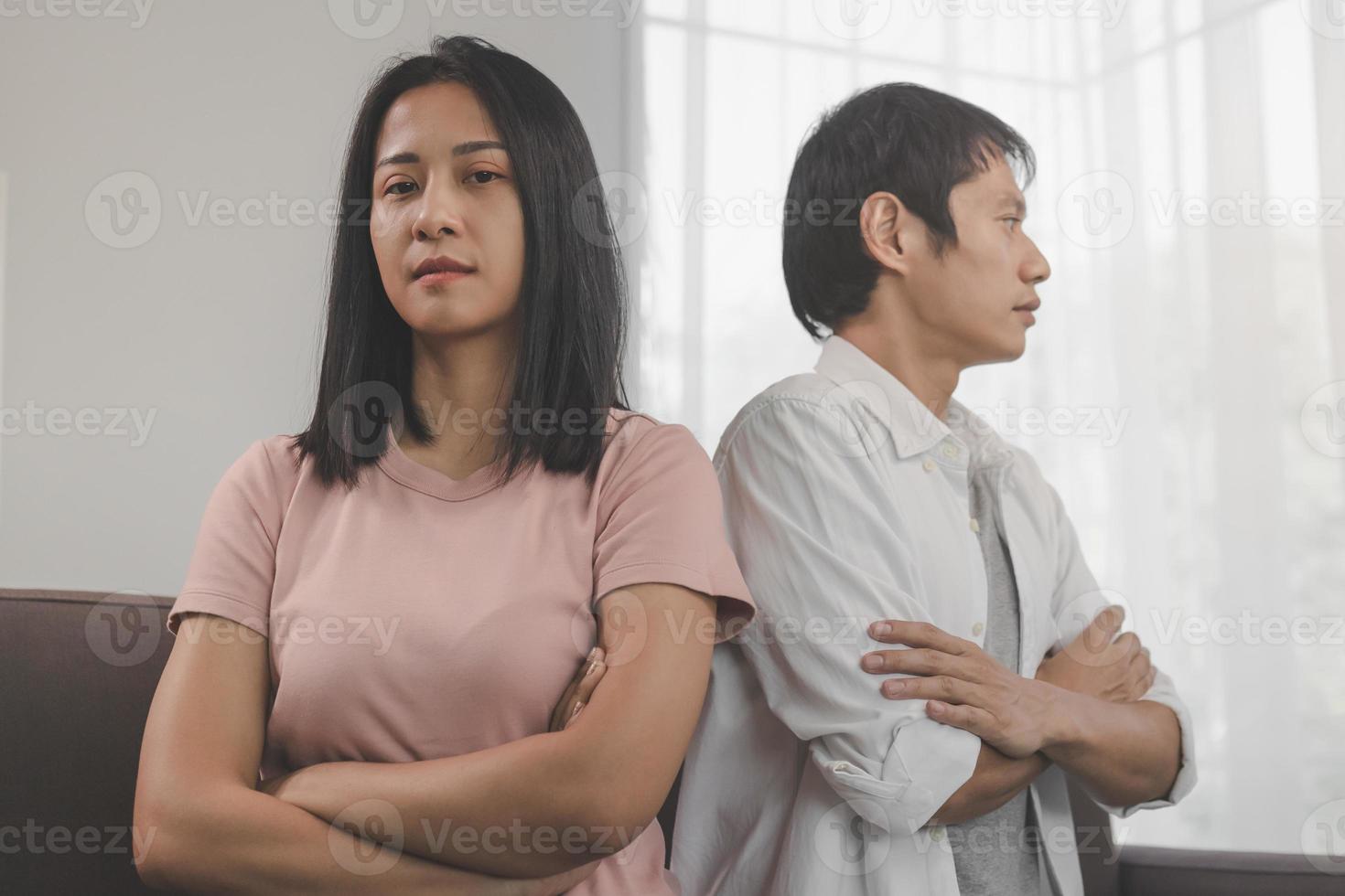 Unhappy young asian couple fights on couch, relationship is in trouble. Different people are angry and use emotions at each other. Husband has an expression of disappointment and upset with his wife. photo