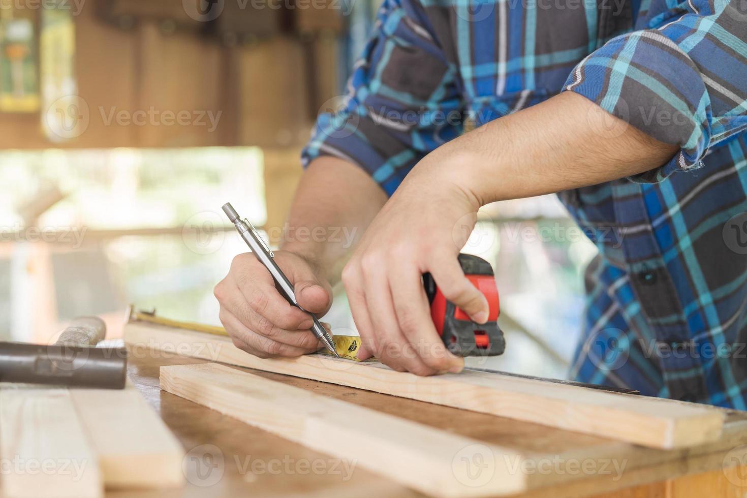 Carpentry professional, hand of asian young man, male carpenter use tape measure, tool on board wood in small shop. Woodwork, furniture making, construction industry. Owner small business people. photo