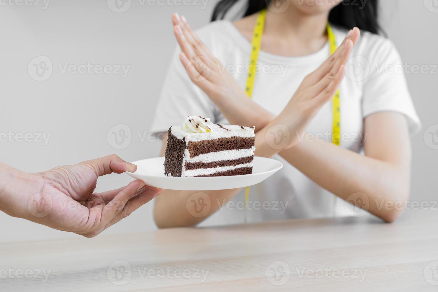 Diet, Dieting unhealthy asian young woman hand in deny, rejecting eat chocolate cake or sweet taste, fighting to keep it from getting fat when people giving to me. Healthy, nutrition of weight loss. photo