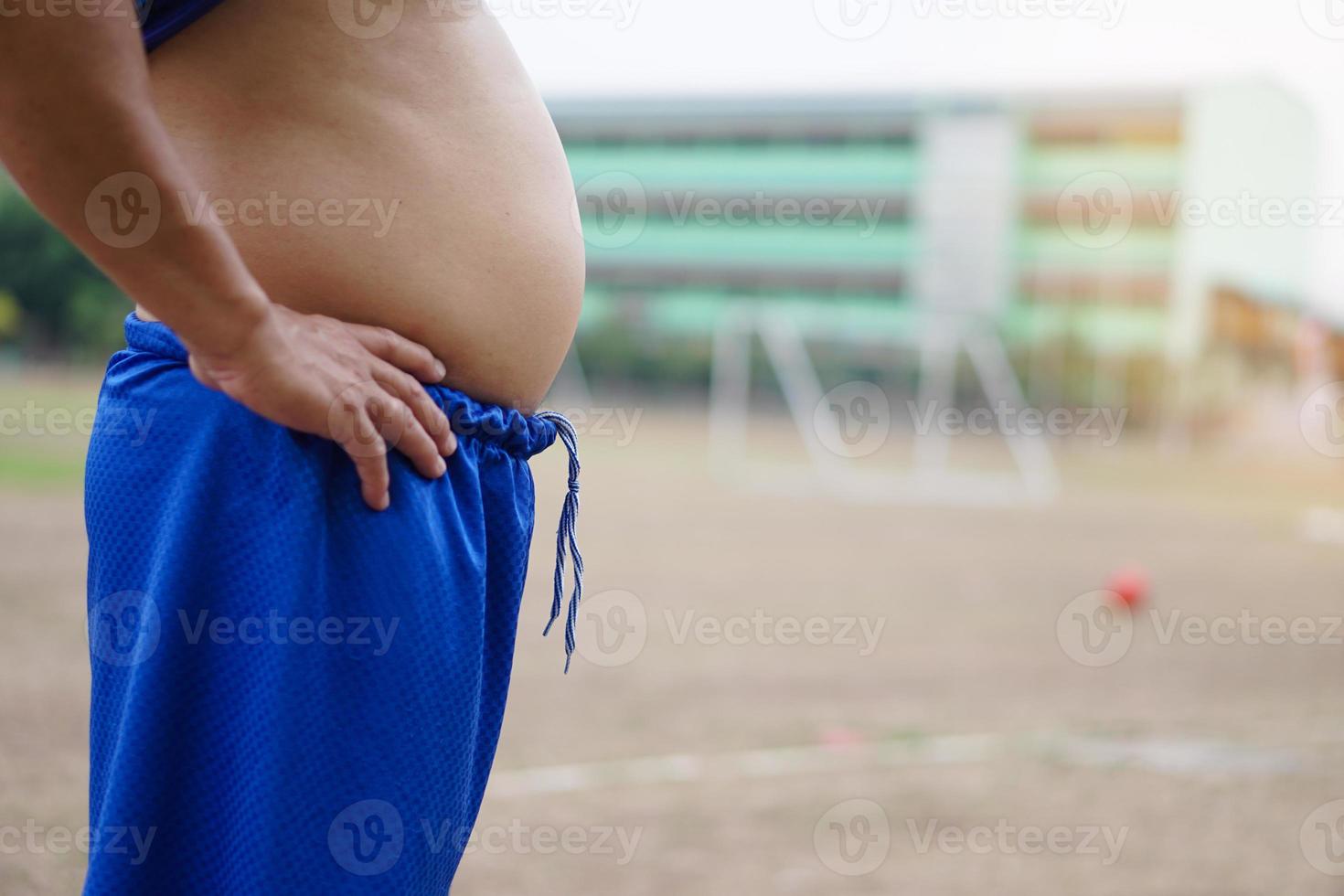 Closeup man shows his big belly, abdomen. Concept, healthcare, health problems, need to exercise or workout for fitness. Overweight or obesity can cause to diseases. photo