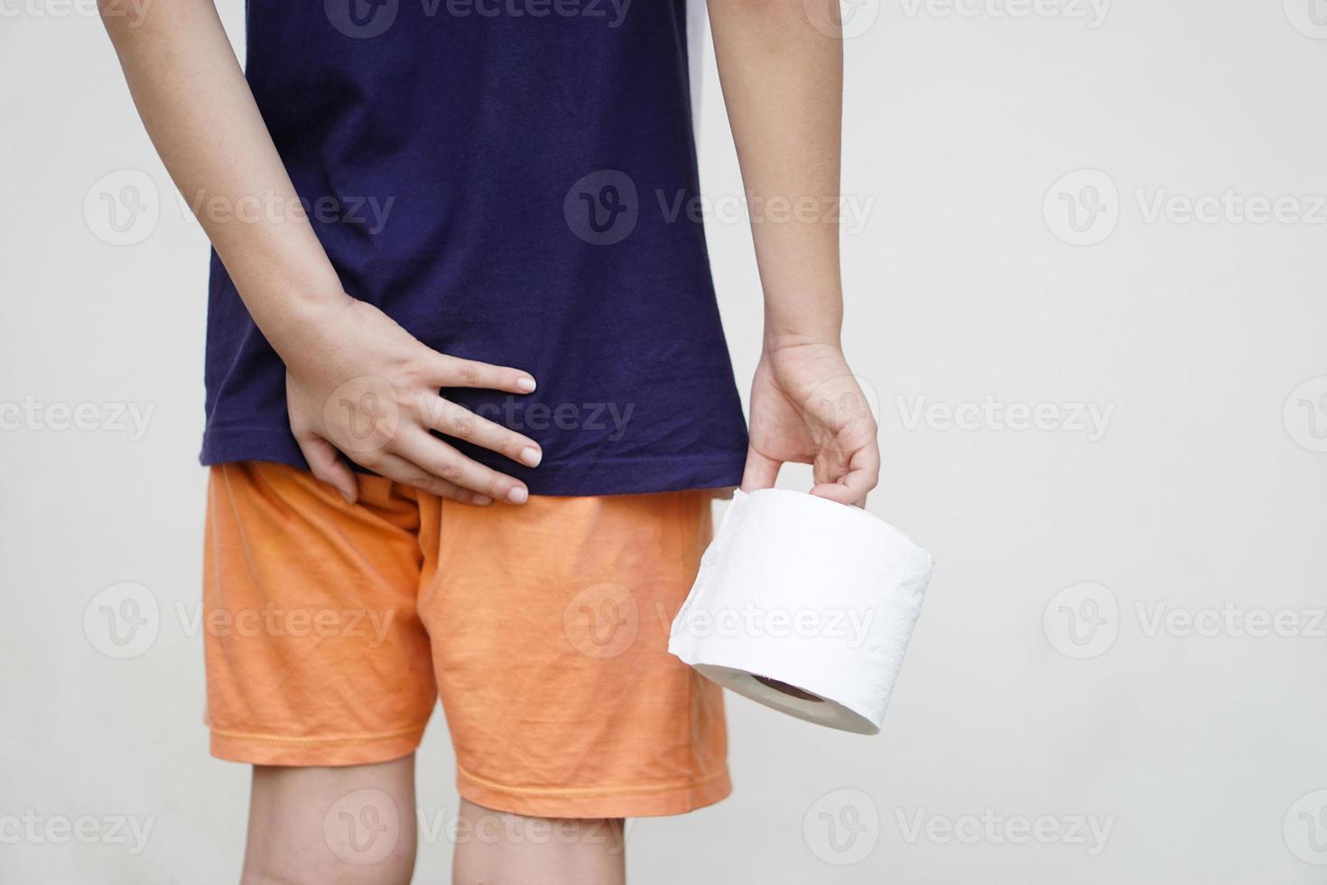 Closeup boy holds roll of tissue paper, need to go to the toilet. Concept, health problem, diarrhoea, hemorrhoids, use tissue paper for hygienic and sanitary.  Health care in daily life. photo