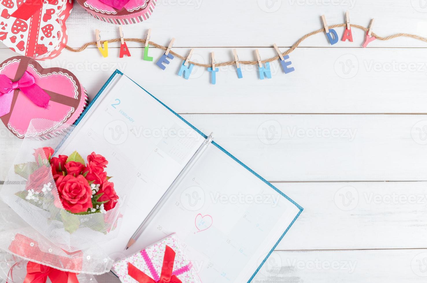 calendar book on  14 February with gift box and red rose bouquet photo