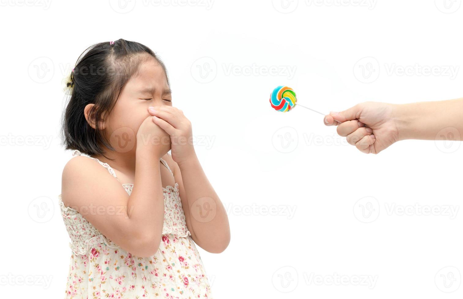 girl with expression of disgust against candy and suffering from toothache photo