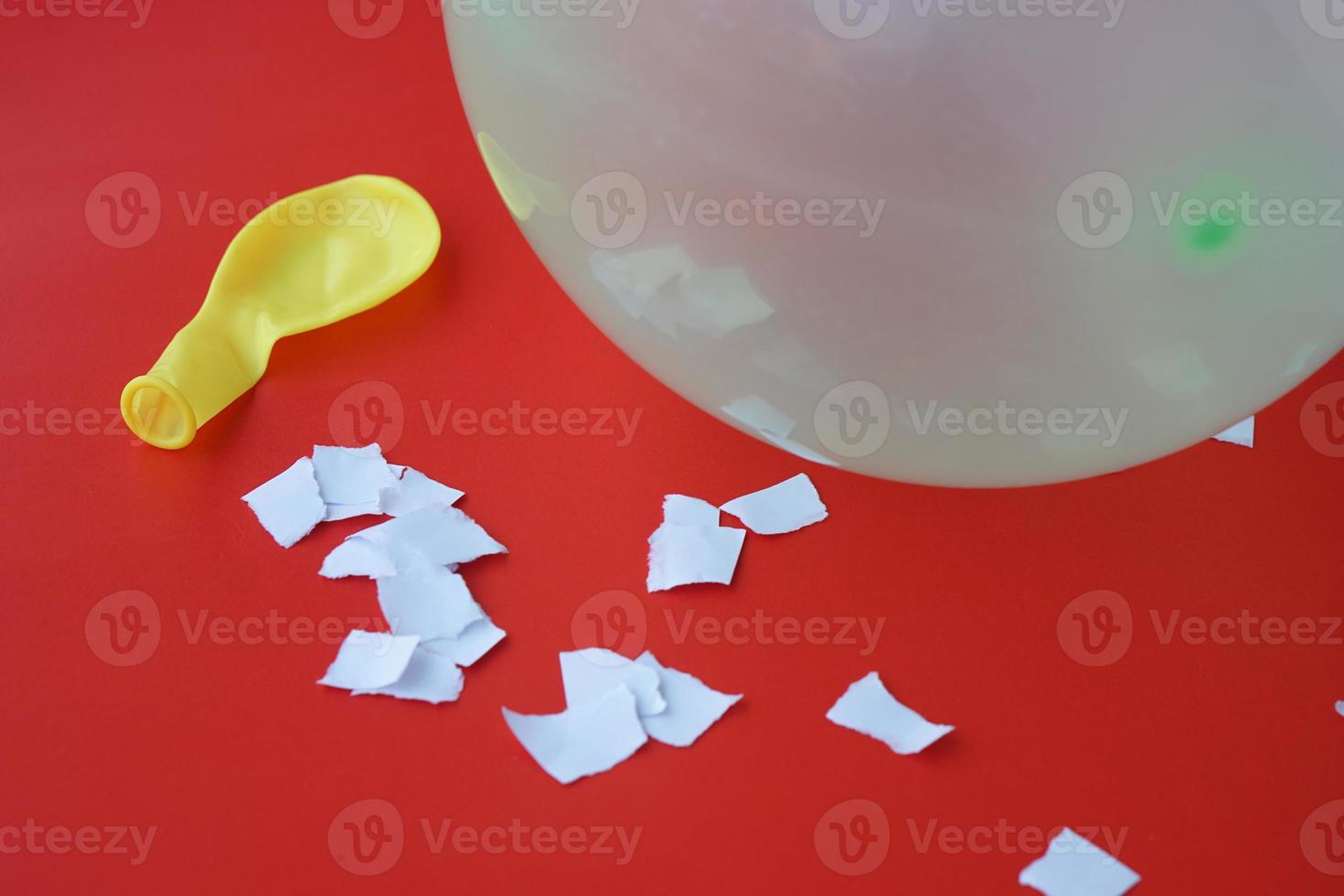 Science experiment about static electricity from balloon and pieces of paper. Red background. Concept, education, science subject. Teaching aid materials. Easy experiment. photo
