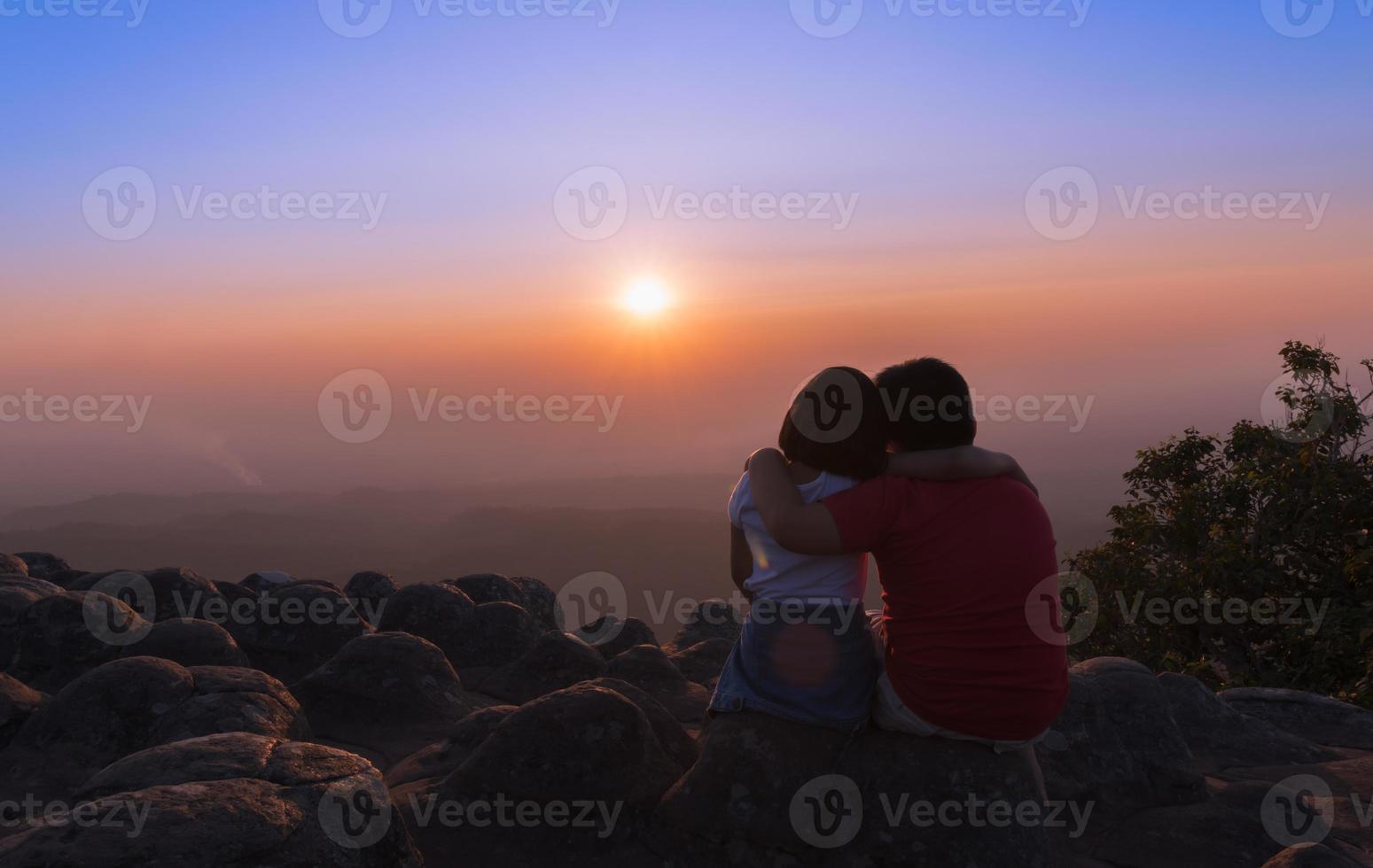 hermano y hermana sentado en rock y ver puesta de sol juntos foto