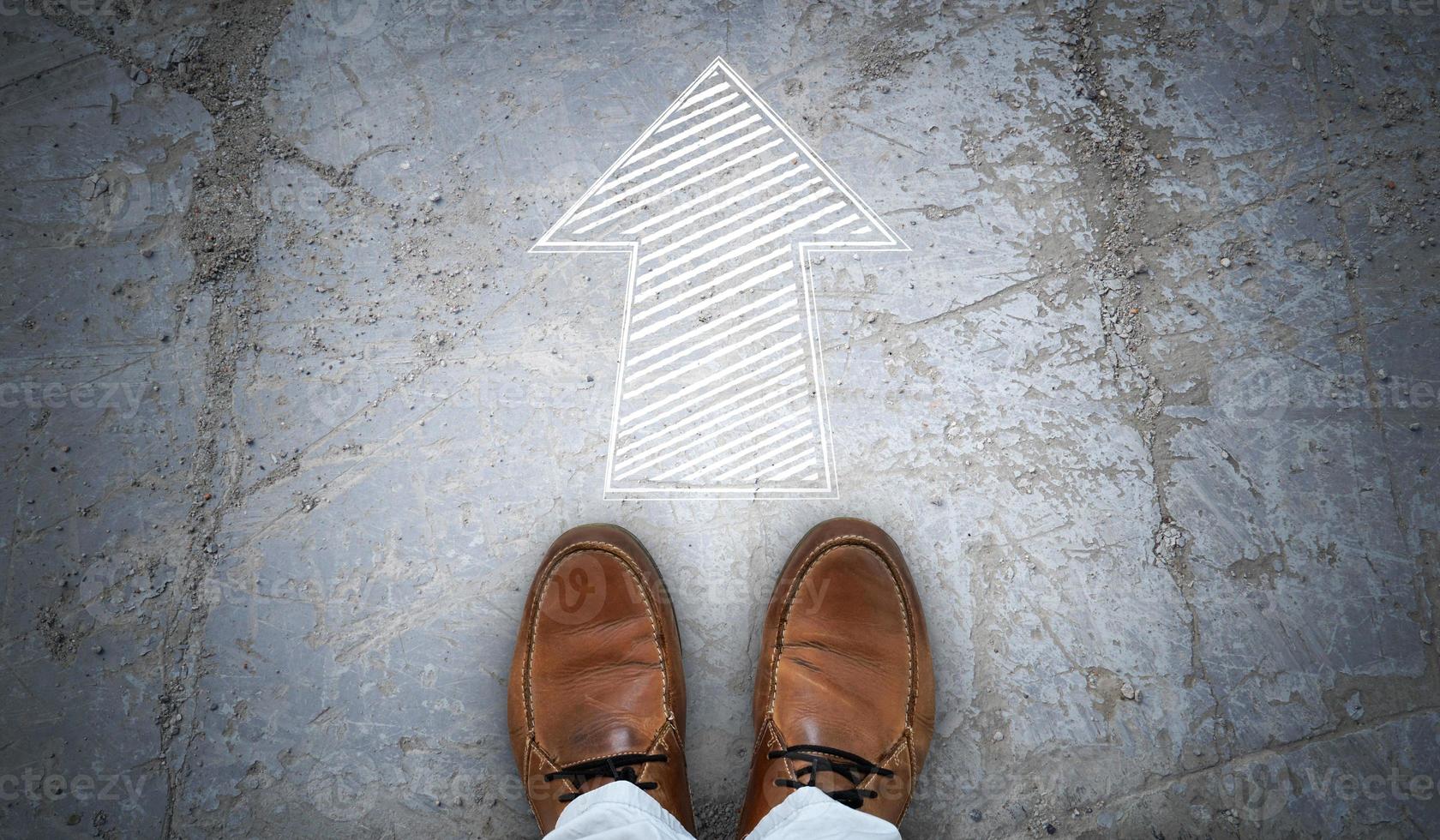 Brown Leather Shoes and Chalky Arrow on Asphalt - Forward Concept photo