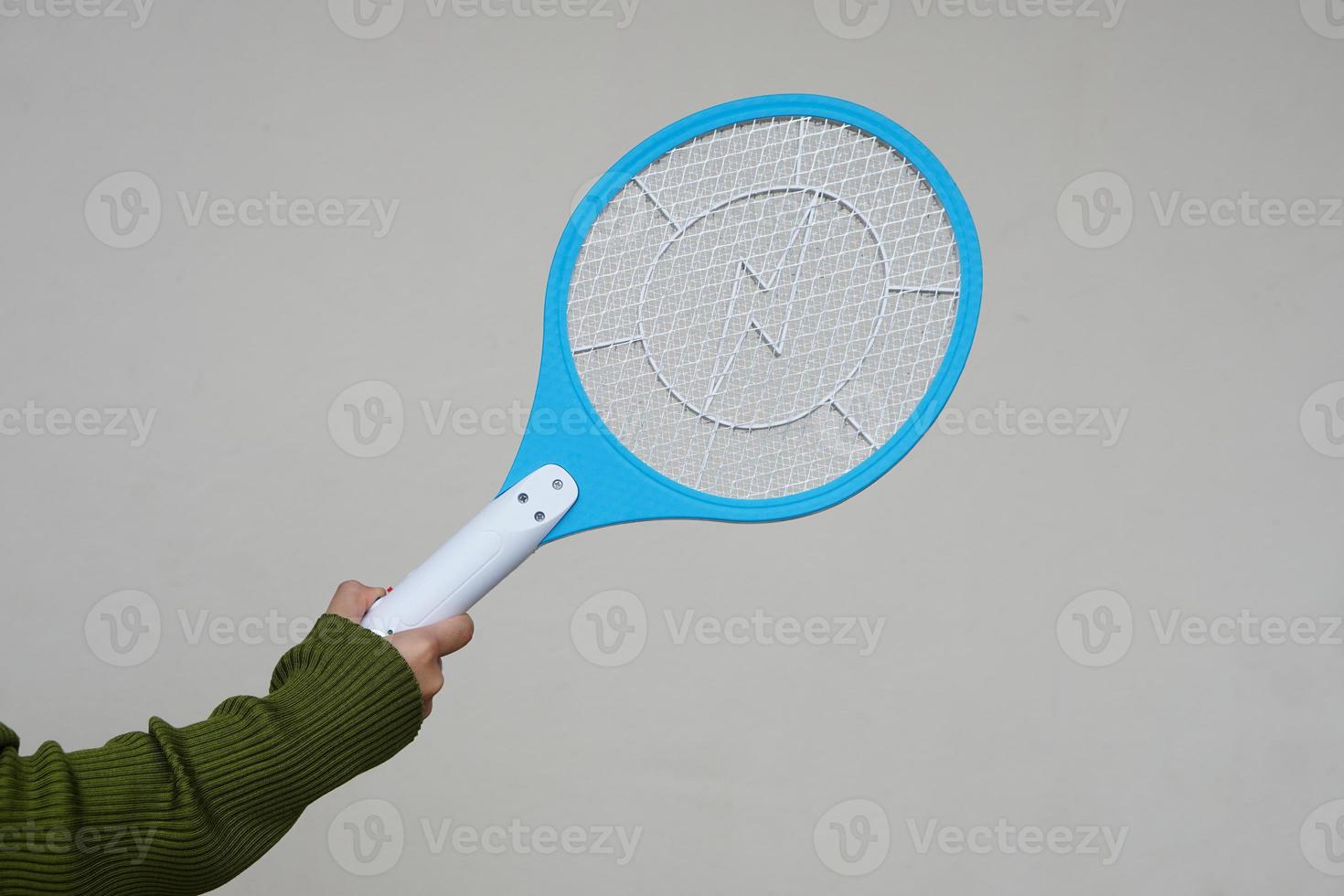 Closeup hand holds mosquito electric swatter racket. Concept, electric device to kill mosquitoes, insects, bugs by swatting to flying insects. photo