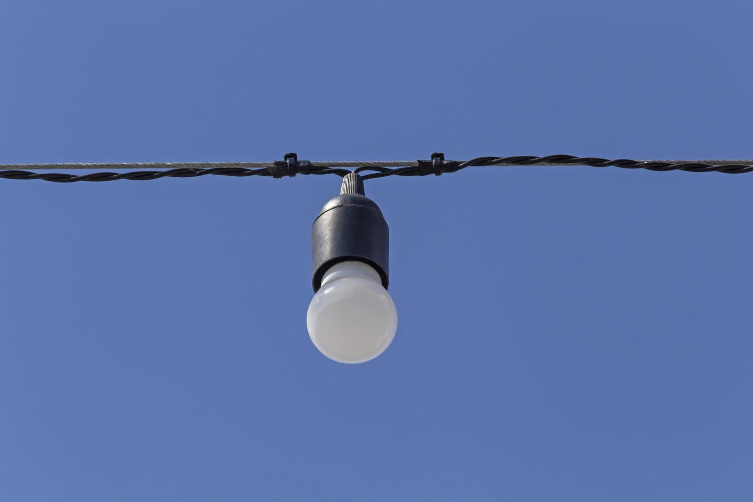 bulb hanging on cable against blue sky photo
