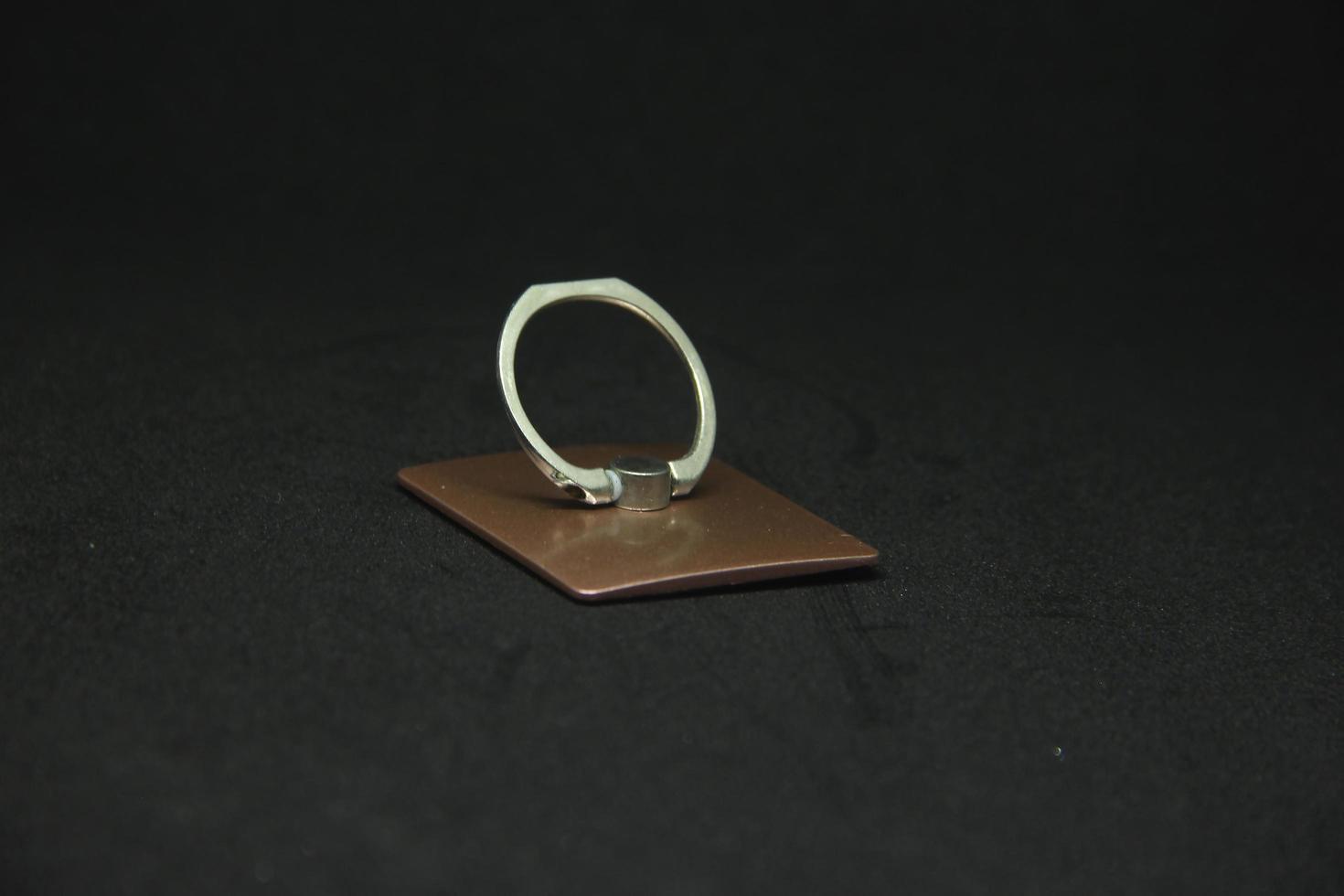 Small cheap thin metal iron phone finger ring grip pop socket to be placed behind the phone. Isolated object photo on black background.