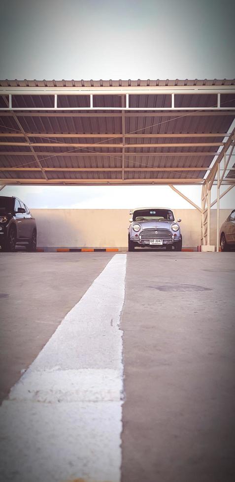 Bangkok, Thailand-March12, 2023  White line road up to Blue classic Mini cooper car parked inside garage in vintage tone and Selective focus. Old vehicle, Transportation, Low angle view photo