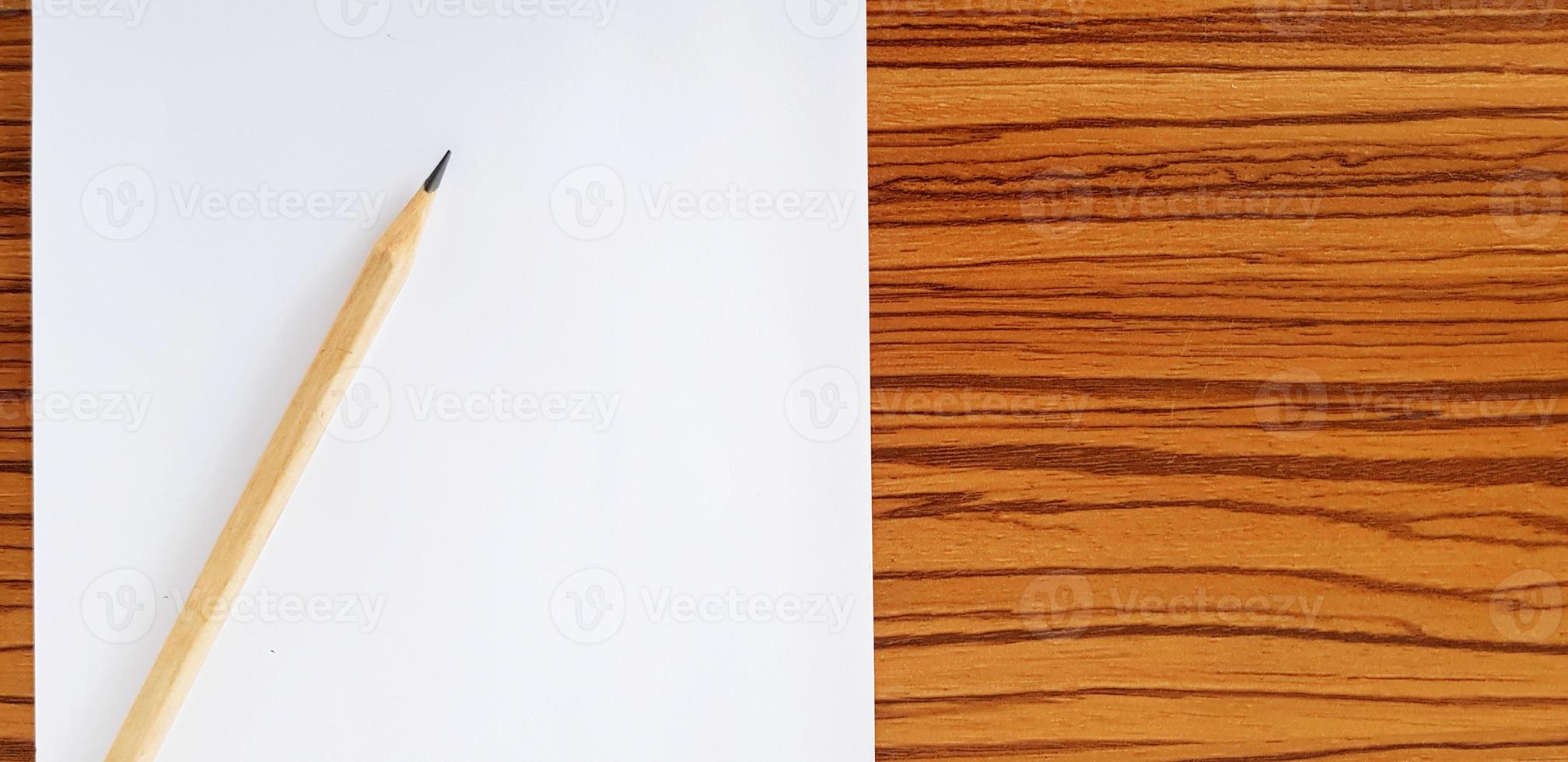 Brown pencil with white paper putting on wooden table with copy space for fill text. Education, Document and Object concept photo