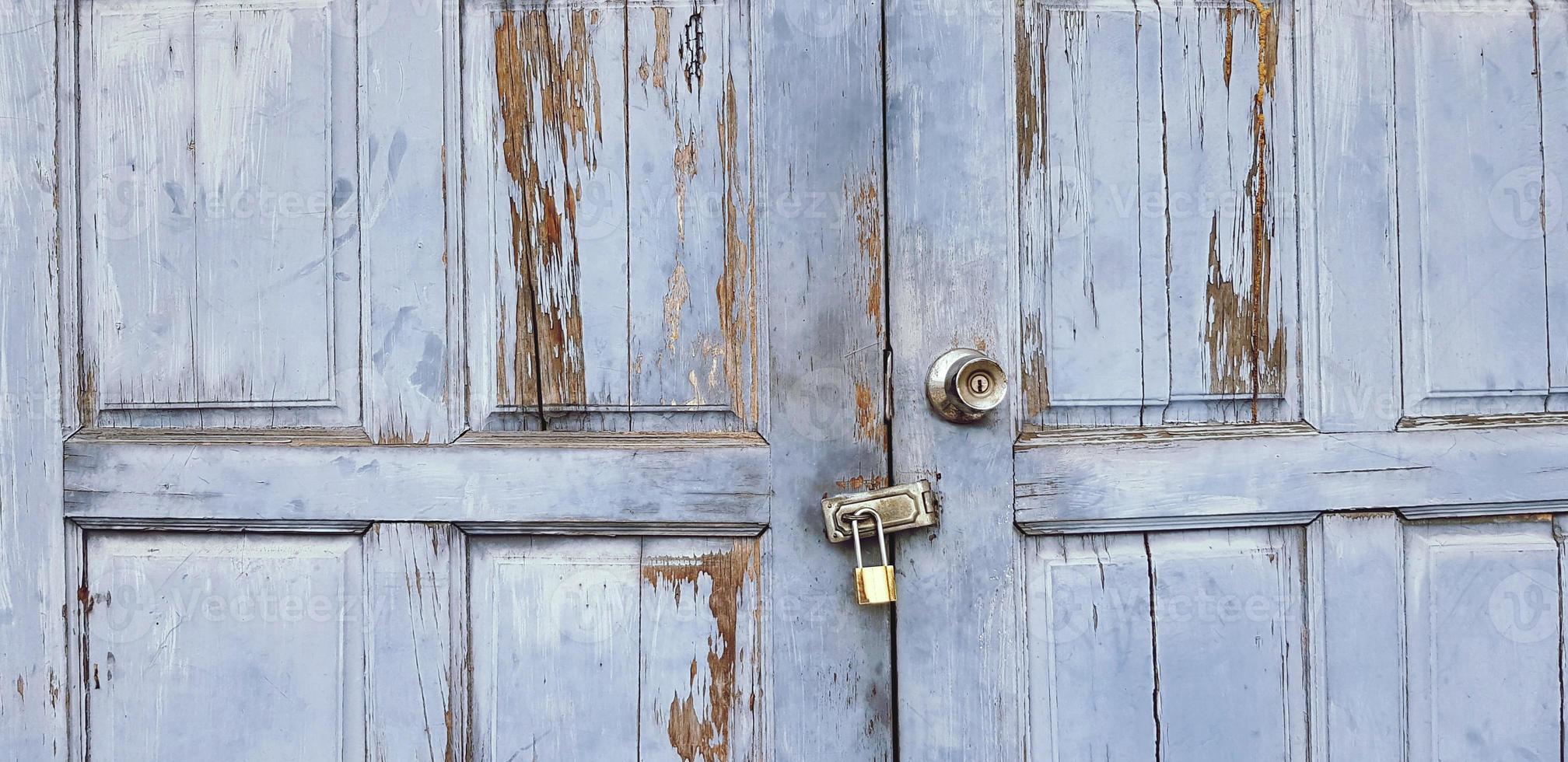 Old grunge or vintage light blue wooden door or window locked with small golden master key for background. Classic object, Wallpaper, Keeping closed and Protect private asset concept photo