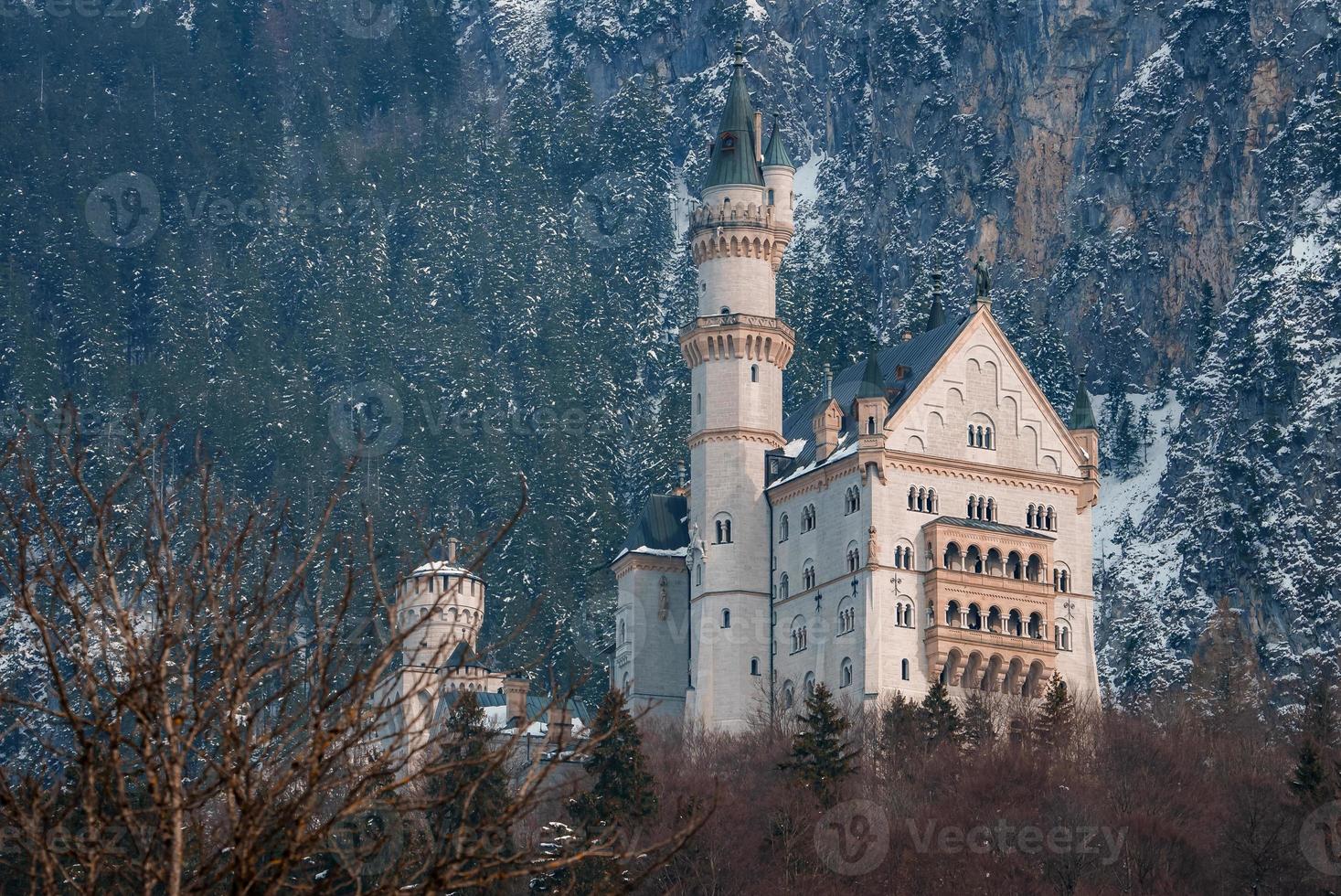 Beautiful view of the Neuschwanstein Castle or Schloss Neuschwanstein  on a winter day, with the mountains and trees capped with snow all around it. photo