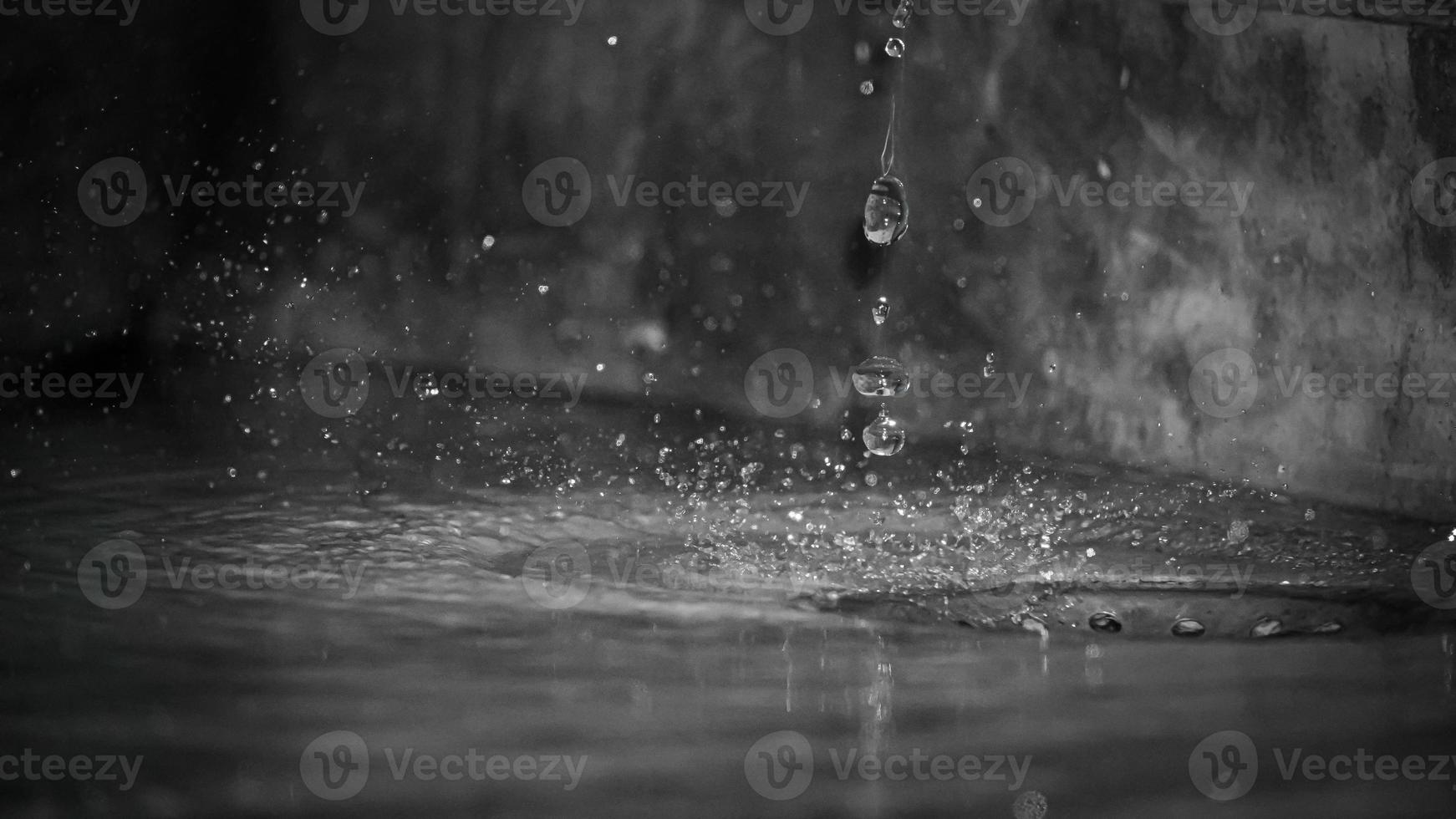 Round rain drops falling on smooth surface of water with grain photo