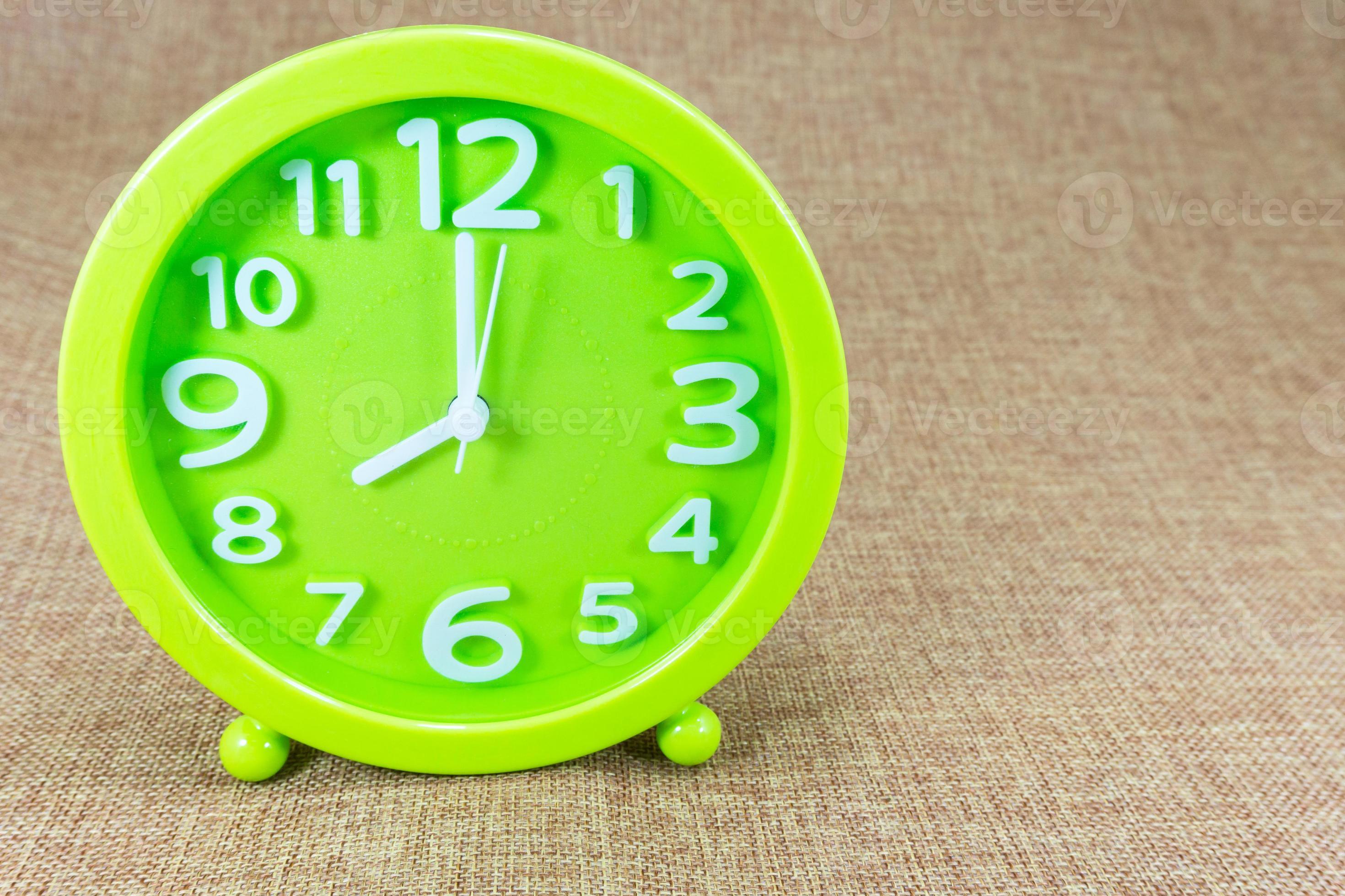 Green alarm clock on brown sackcloth background show Eight o'clock or 8