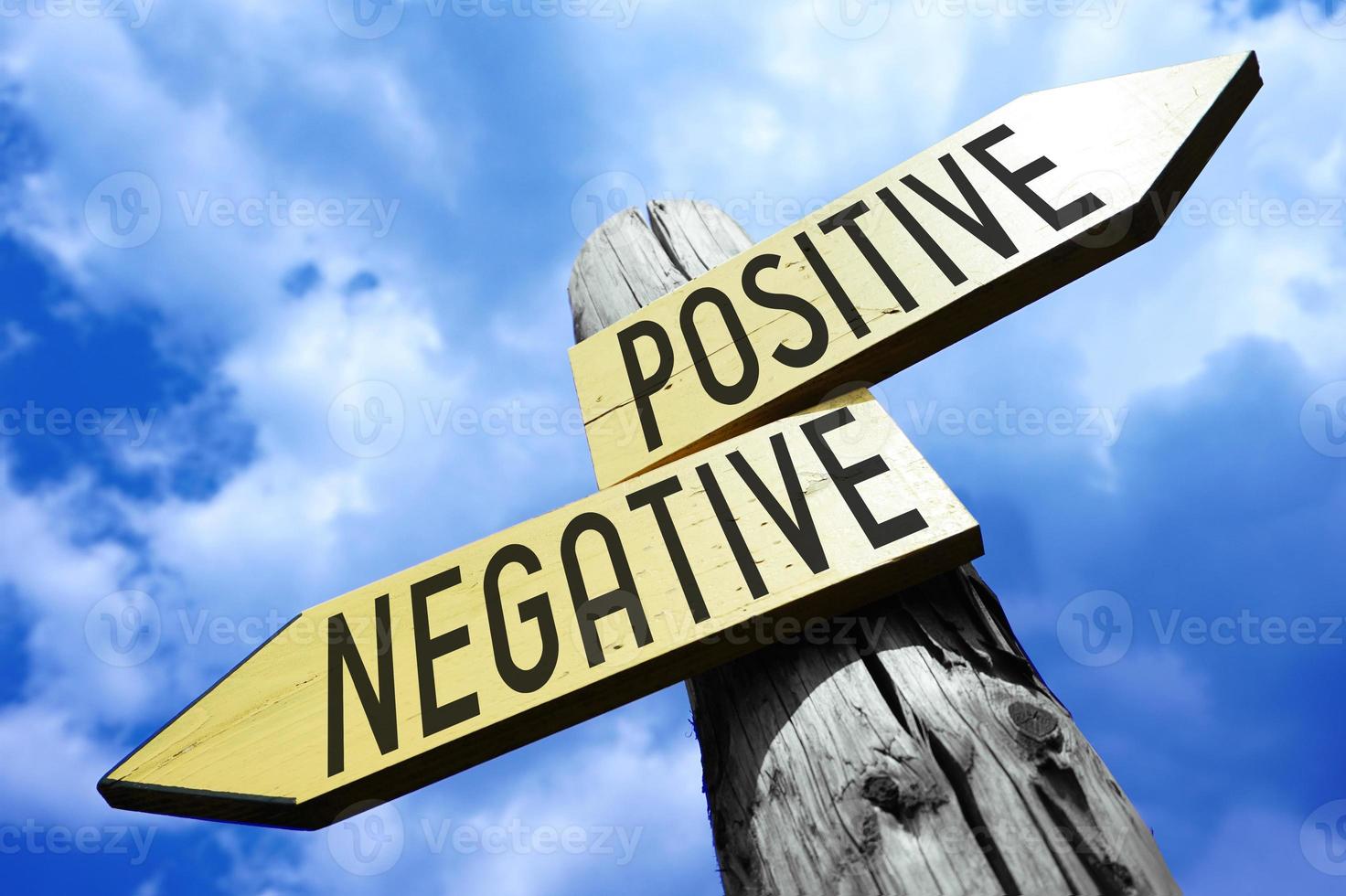 Positive, Negative - Wooden Signpost with Two Arrows and Sky in Background photo