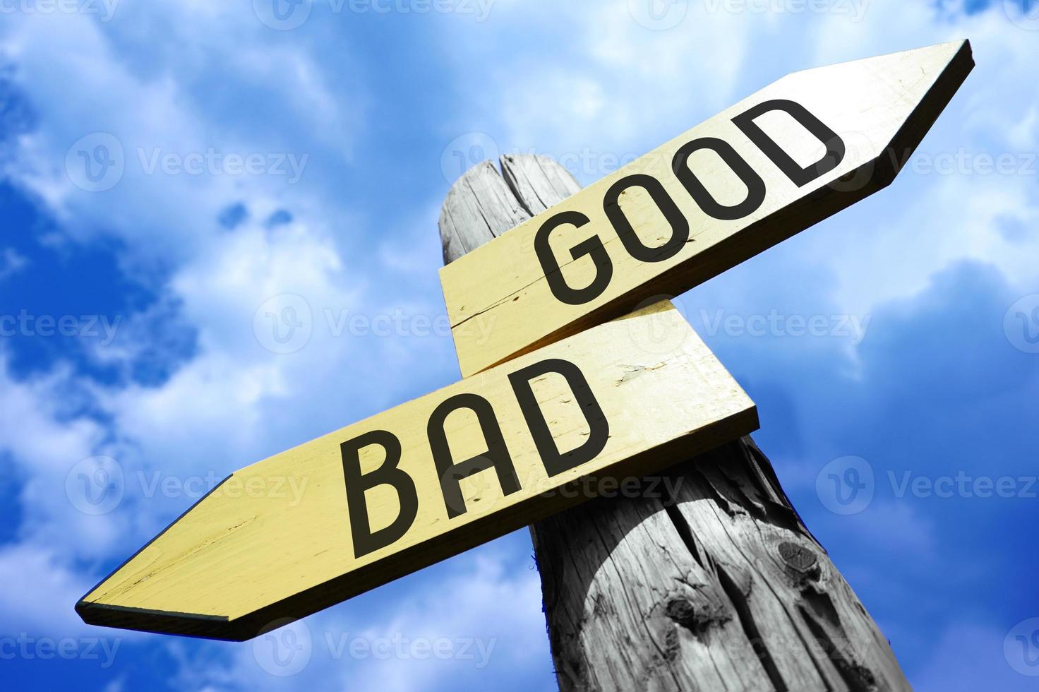 Good, Bad - Wooden Signpost with Two Arrows and Sky in Background photo