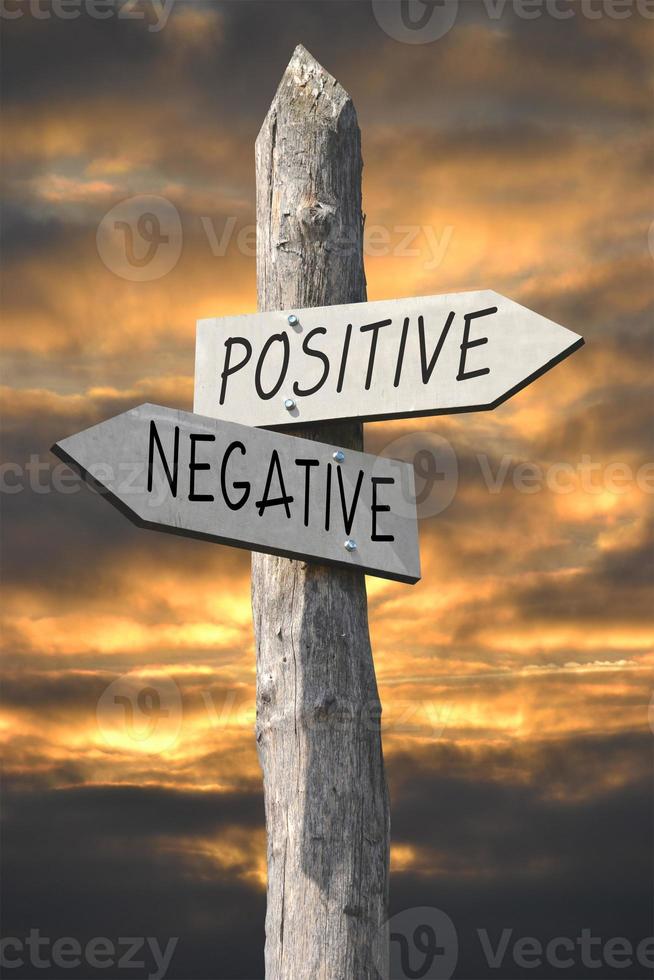 Positive or Negative - Wooden Signpost with Two Arrows and Sunset Sky photo