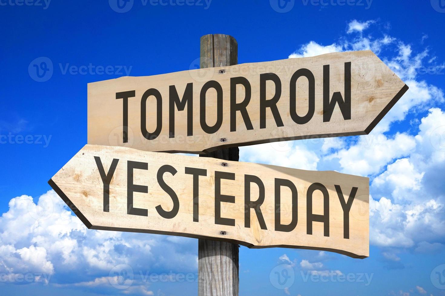 Tomorrow, Yesterday - Wooden Signpost with Two Arrows, Sky with Clouds in Background photo