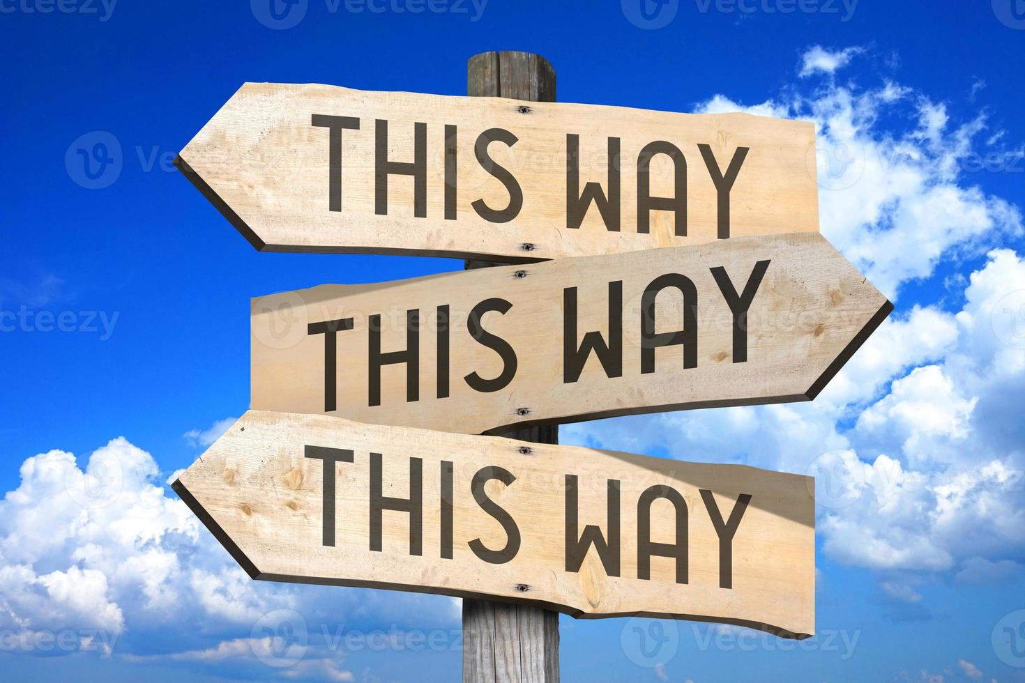 This Way Concept - Wooden Signpost with Three Arrows, Sky with Clouds in Background photo