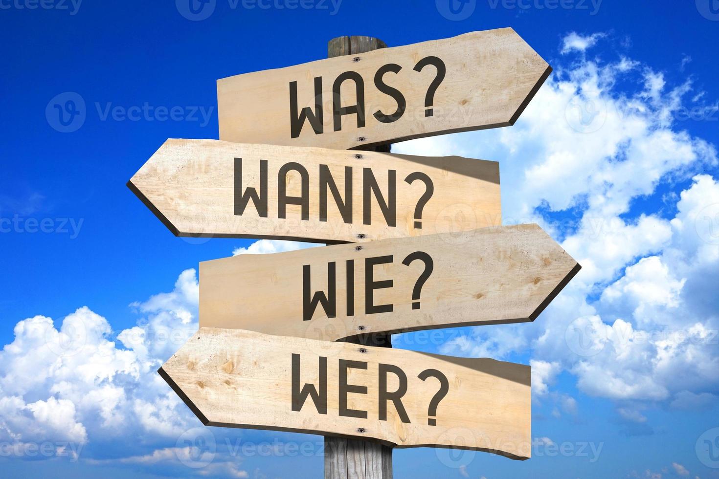 What, When, How, Who Questions in German - Wooden Signpost with Four Arrows photo