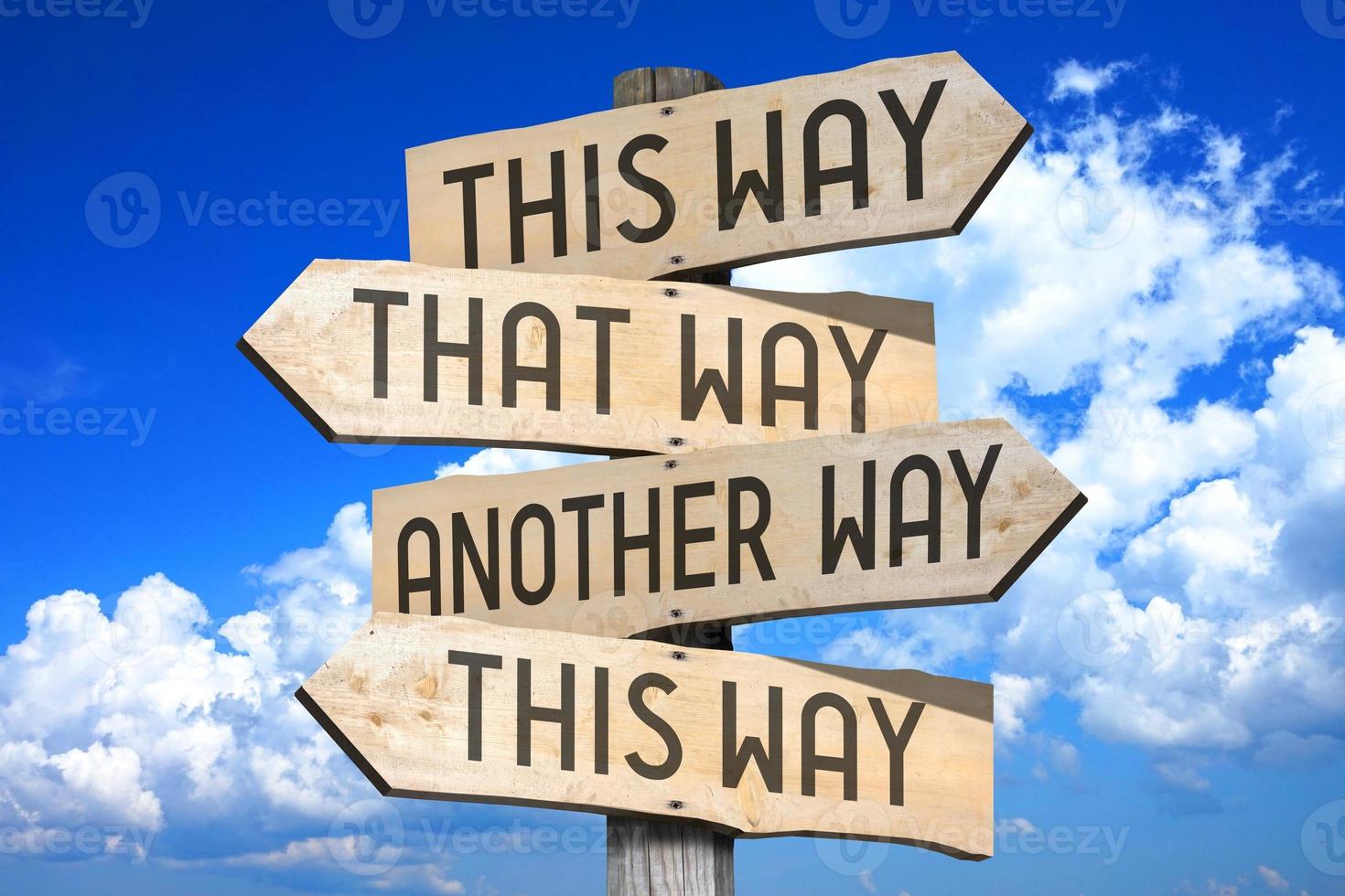 This Way, That Way, Another Way - Wooden Signpost with Four Arrows, Sky with Clouds in Background photo