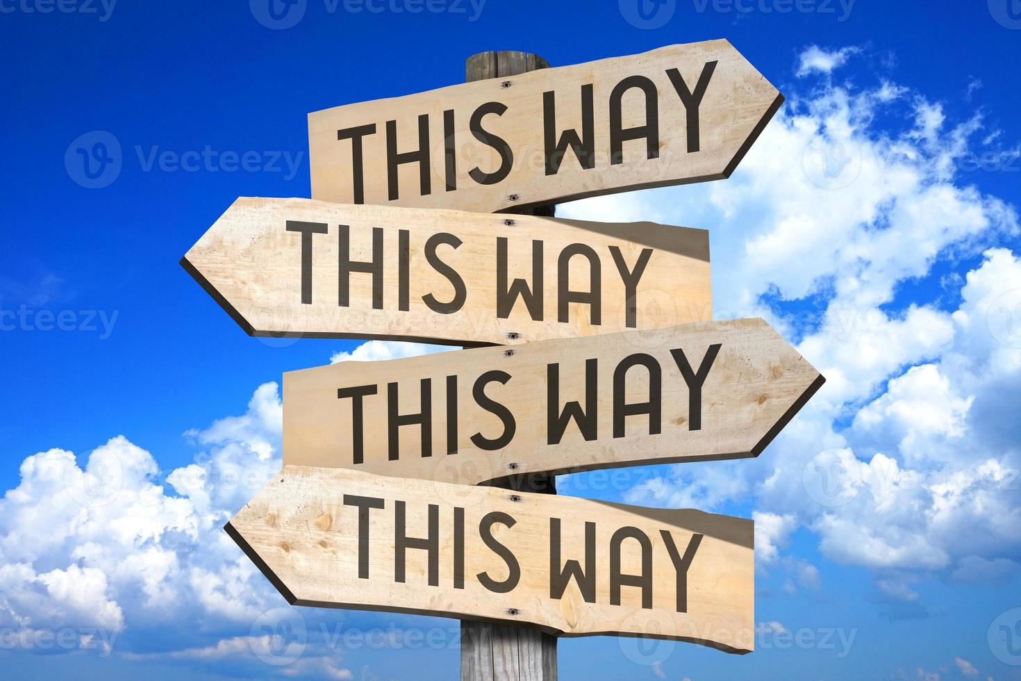 This Way - Wooden Signpost with Four Arrows, Sky with Clouds in Background photo