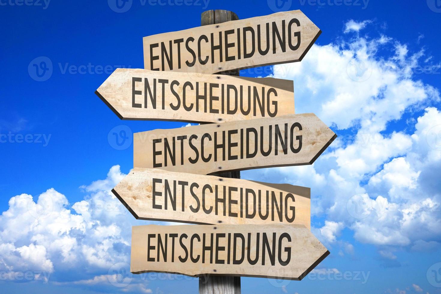 Decision in German - Wooden Signpost with Five Arrows, Sky with Clouds in Background photo