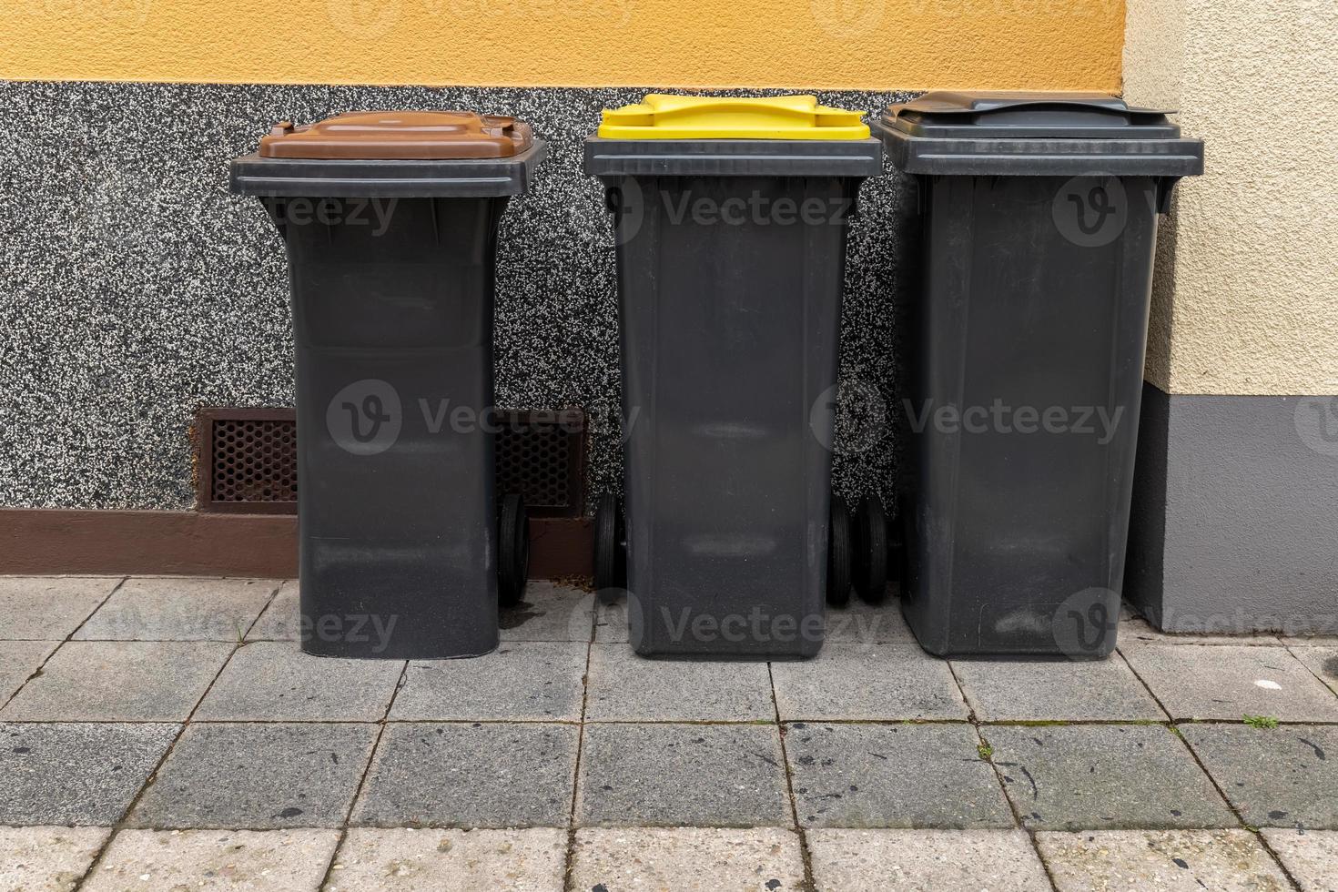 three garbage cans in front of a house photo