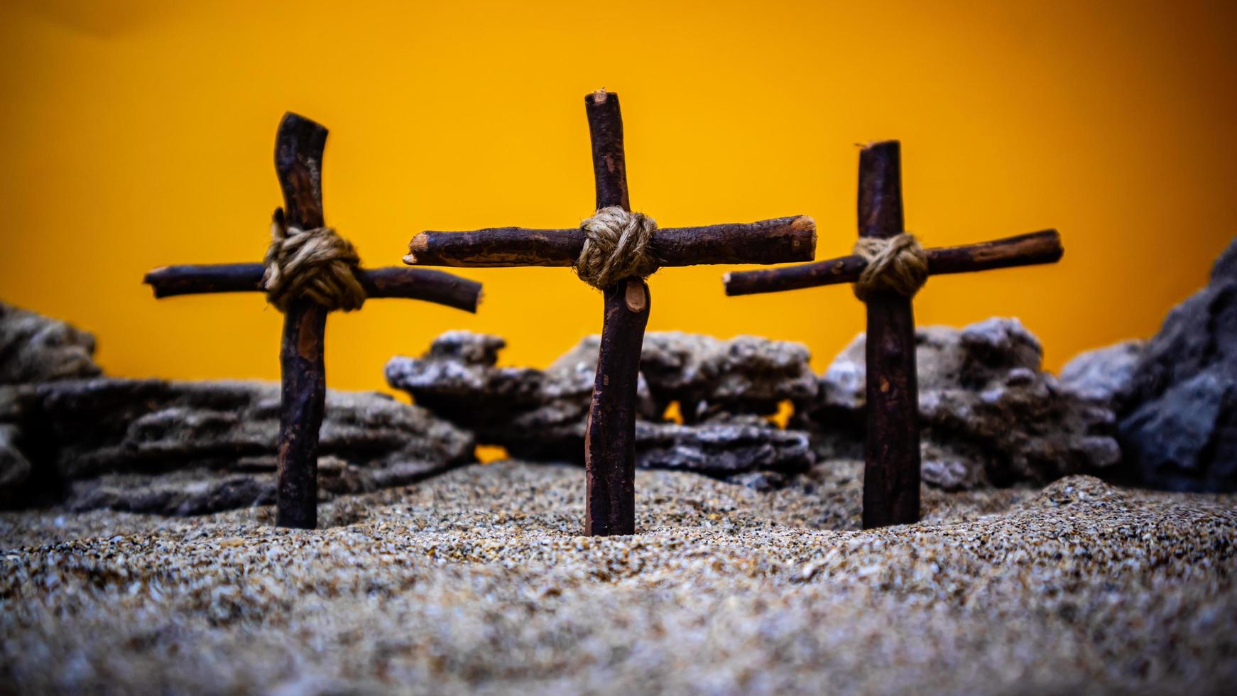 cruces atascado en el arena en un naranja antecedentes foto