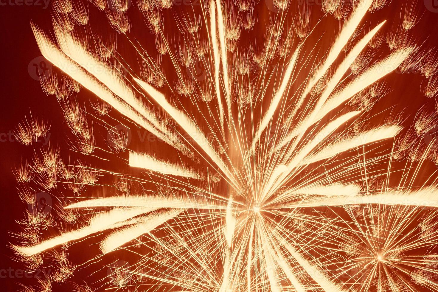 bright yellow fireworks against dark red background photo