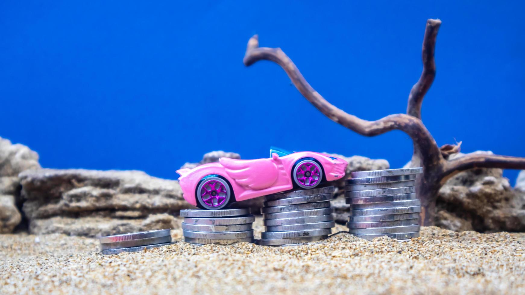 minahasa, Indonesia  January 2023, toy car on a pile of coins, saving for the future, managing successful transportation business technology concept photo