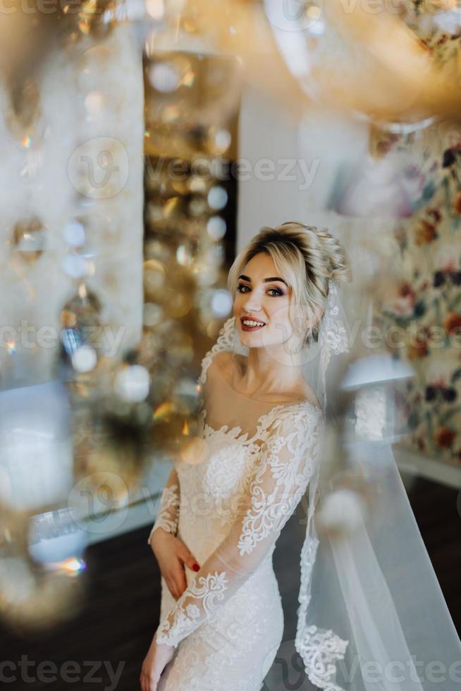 The charming bride is standing in the hotel's lobby near the chandelier photo
