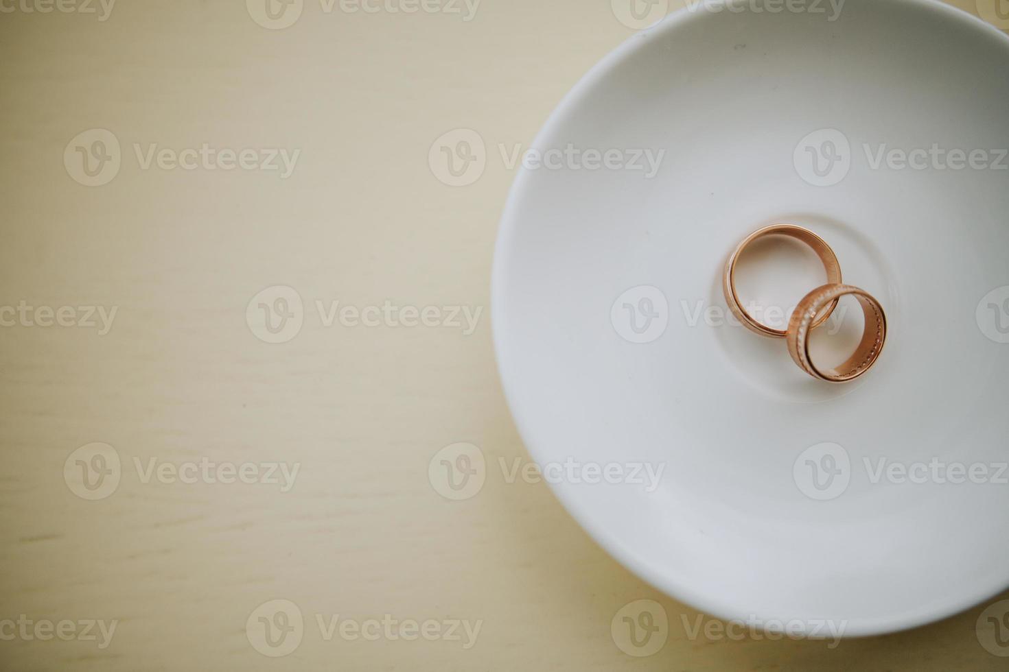 Golden wedding rings on white plate photo